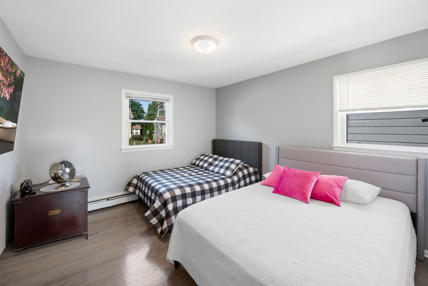 Large bedroom with two windows and grey walls, featuring two beds.