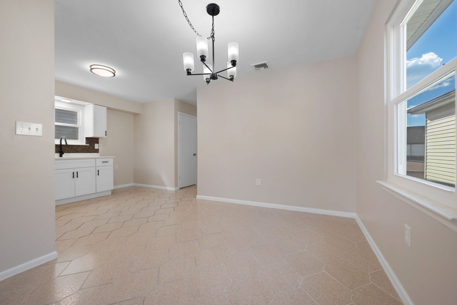 Cozy dining room connected to kitchen featuring a premium light fixture and window.