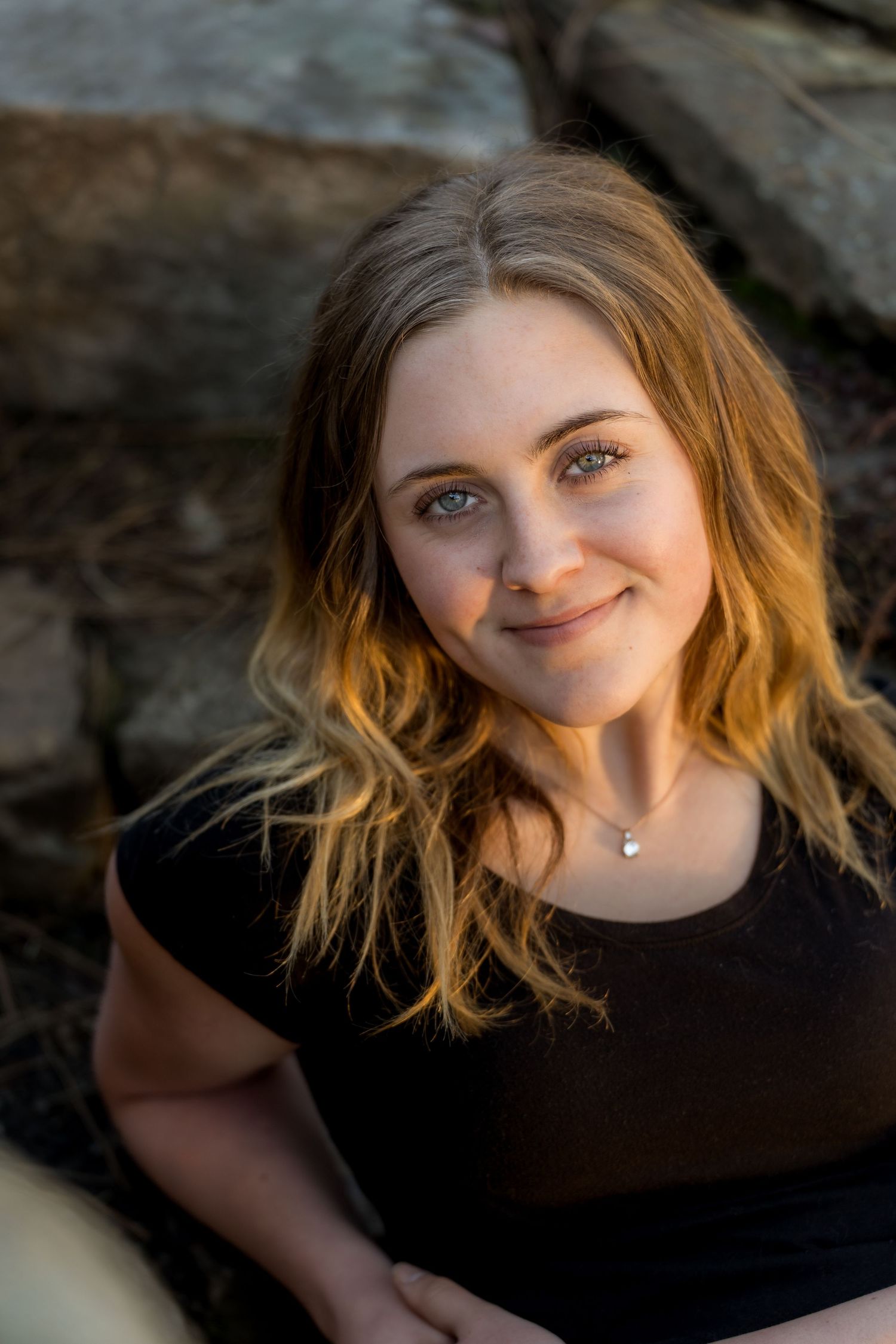 Natural portrait with warm lighting against rocky background.