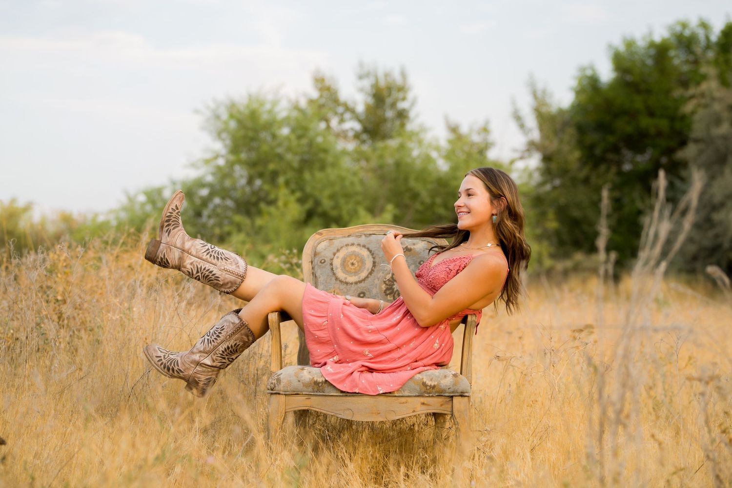 Senior girl standing in a field captured by Dillon Lane Photography with warm golden hour lighting and natural style.