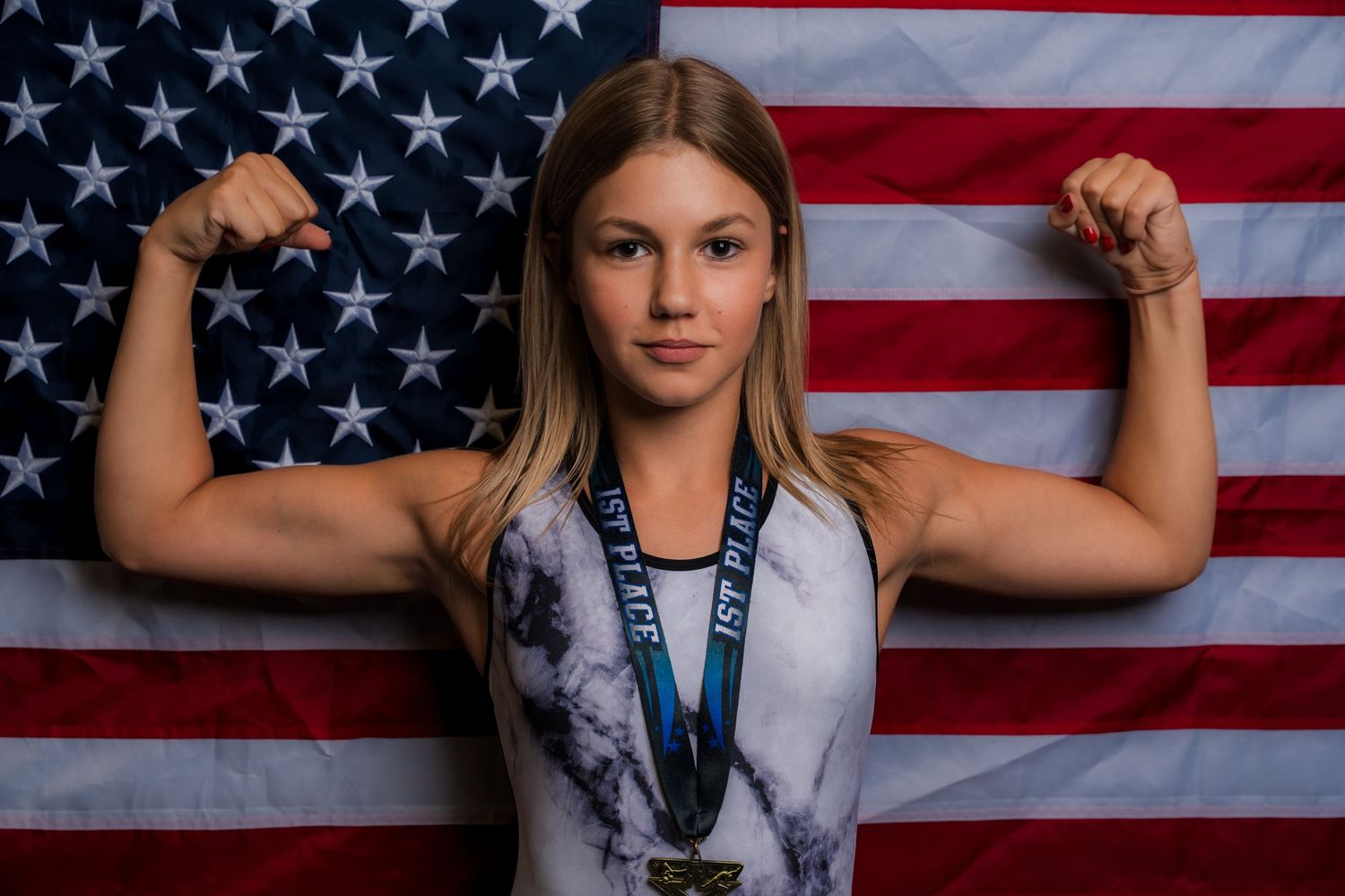 Athlete flexing in front of American flag wearing medal captured by Dillon Lane Photography in Tri Cities WA.