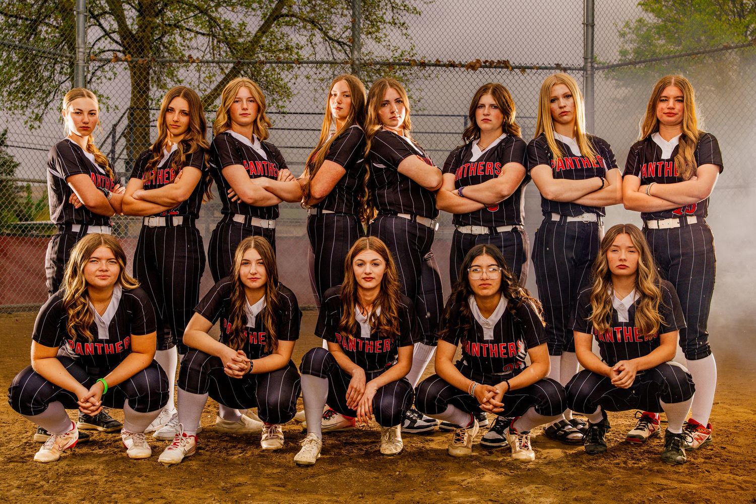 Softball team sits in uniform for team photo.