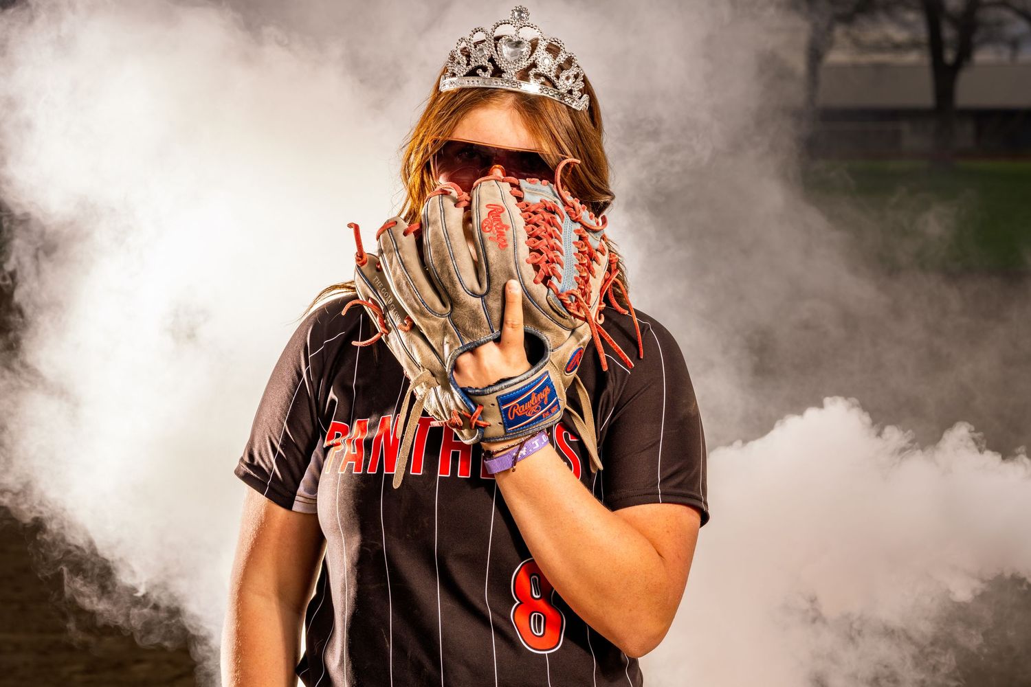 Softball players showcase equipment and uniforms in smoke.