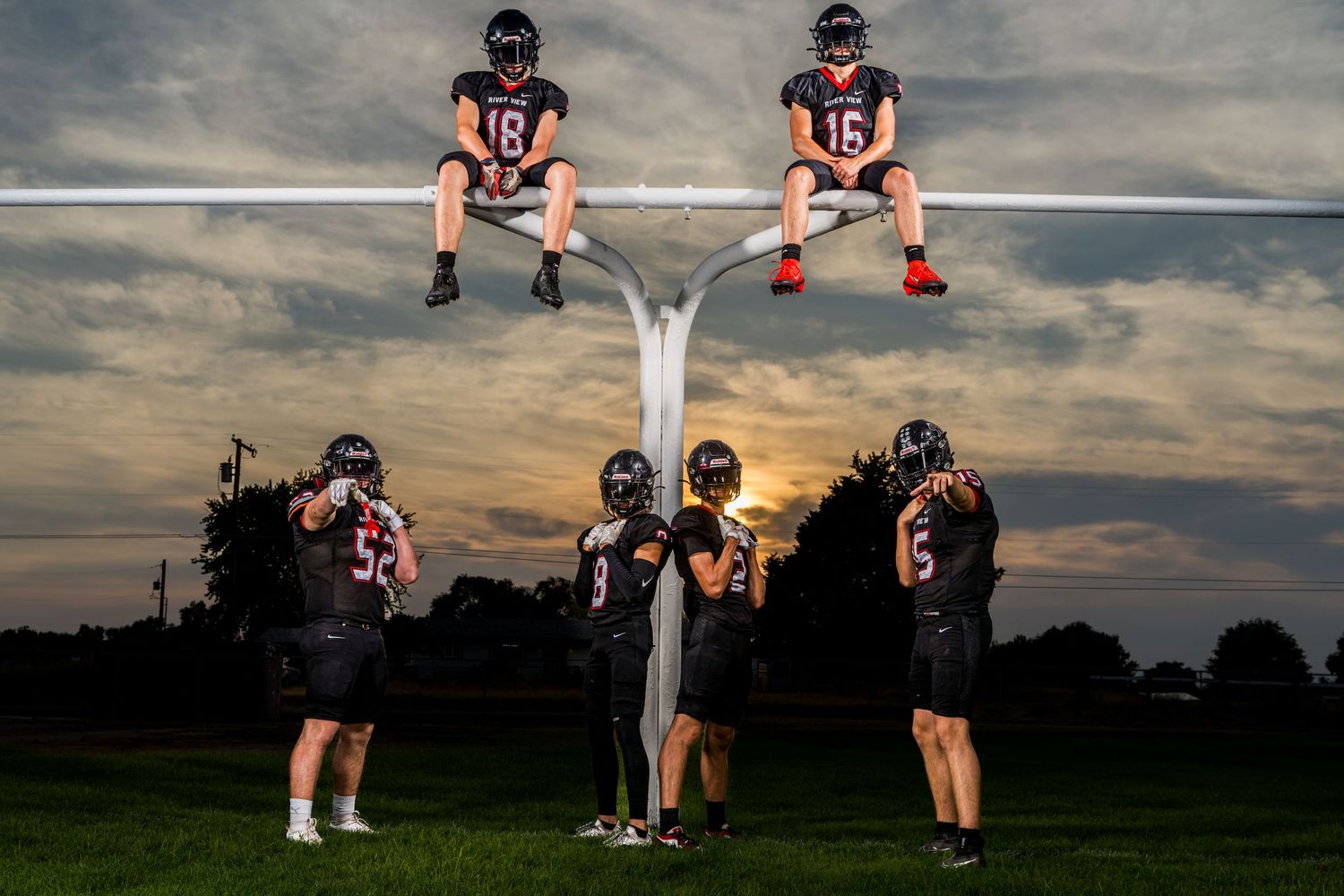 Football Media Day photo in Tri Cities WA with players posing on goalpost captured by Dillon Lane Photography at sunset Eastern Washington.