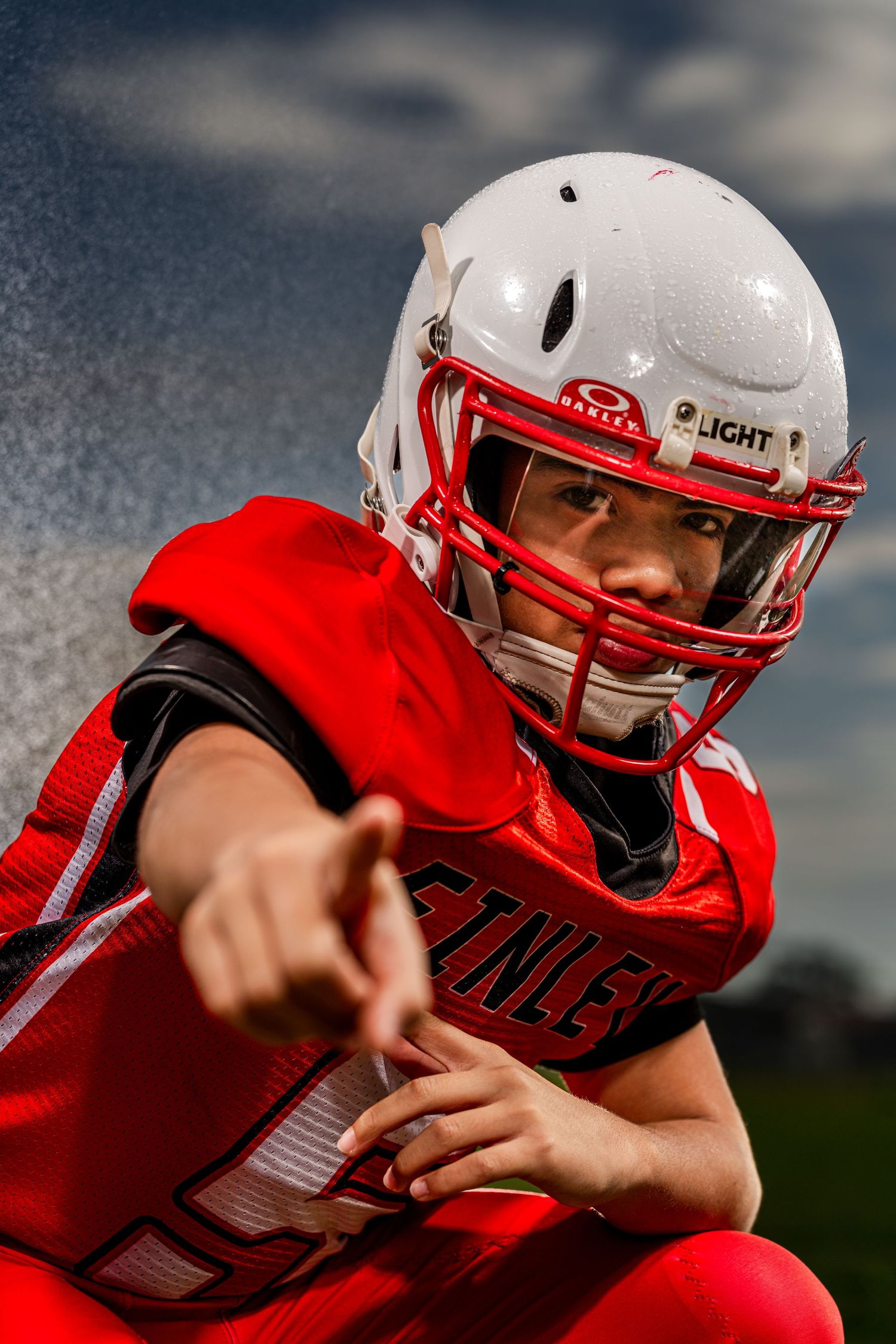 Youth football player in red jersey and white helmet practicing throwing drills during training session.