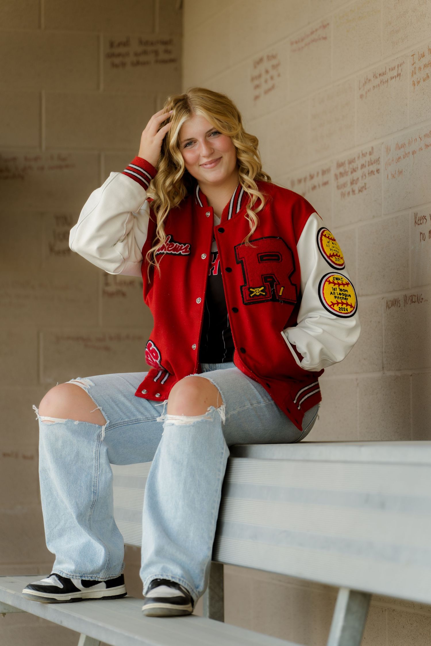 Person wearing varsity jacket sitting on bleachers.