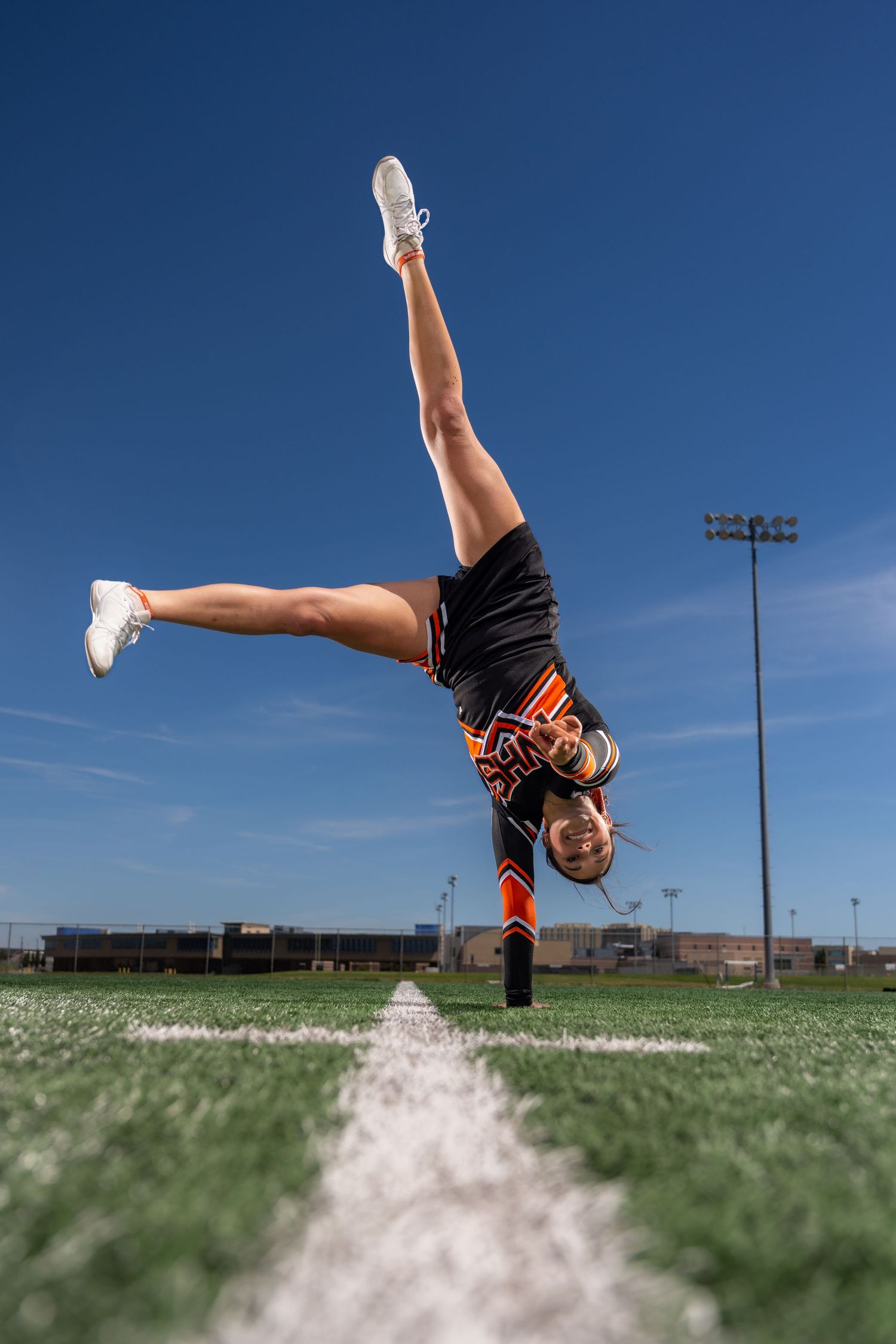 Sequence of athletic flip performed on grass field against blue sky background.