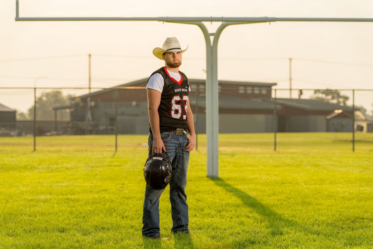 Senior standing in a football field with a goal post in the distance.