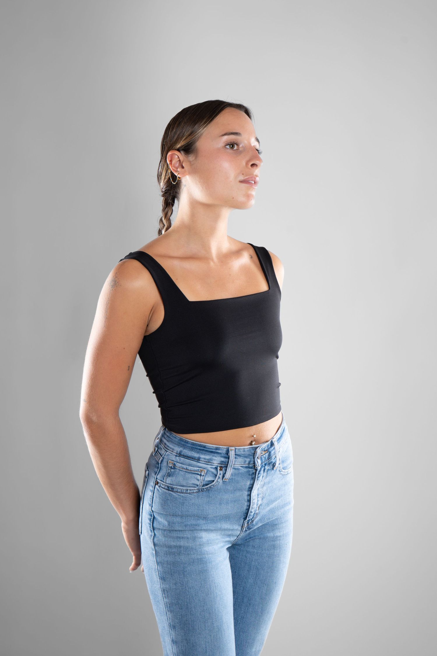 shooting photo studio en fond blanc avec une femme de profil portant un jean bleu et un top noir
