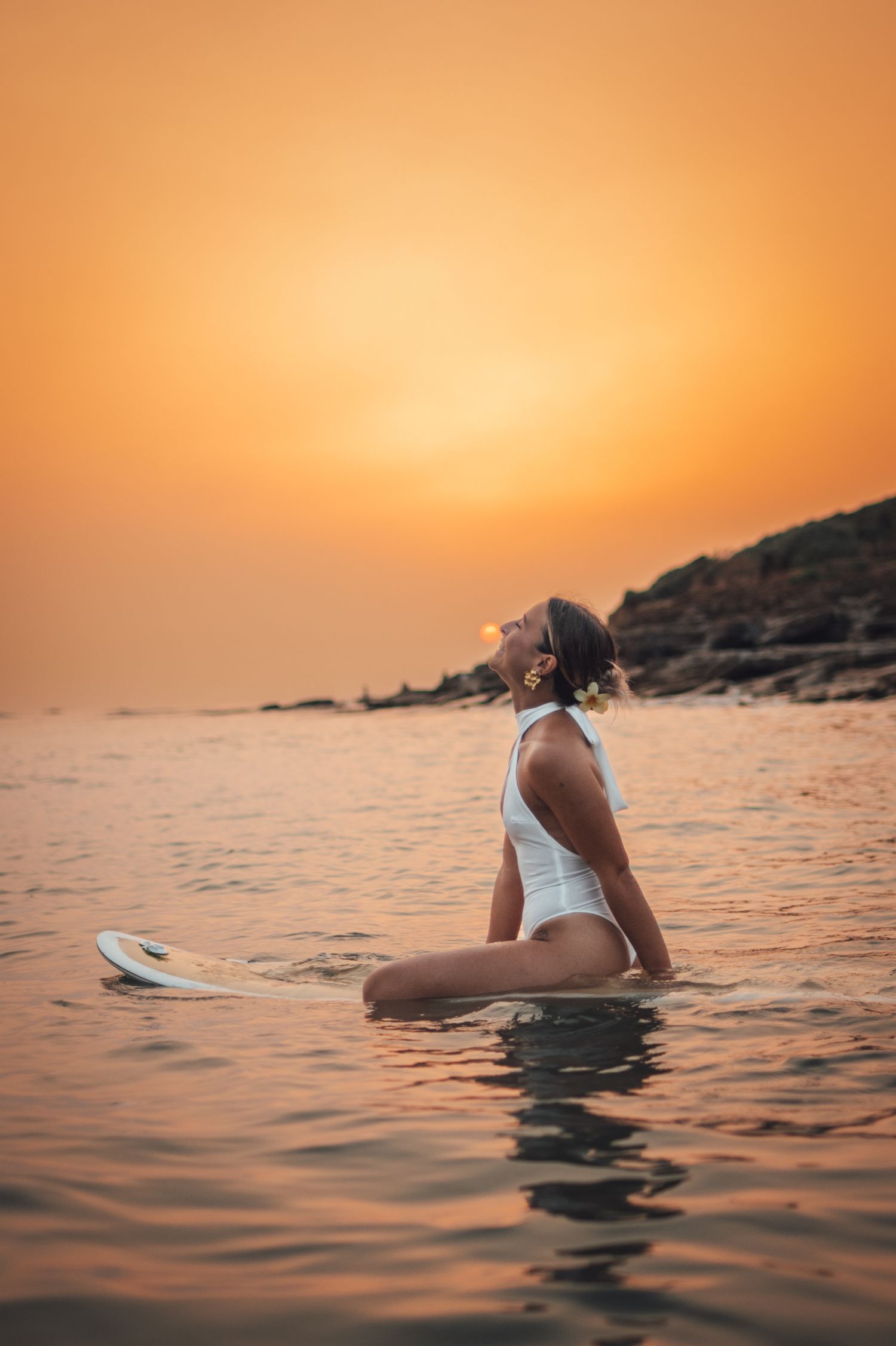 shooting photo surf en couché de soleil avec une femme en maillot de bain blanc