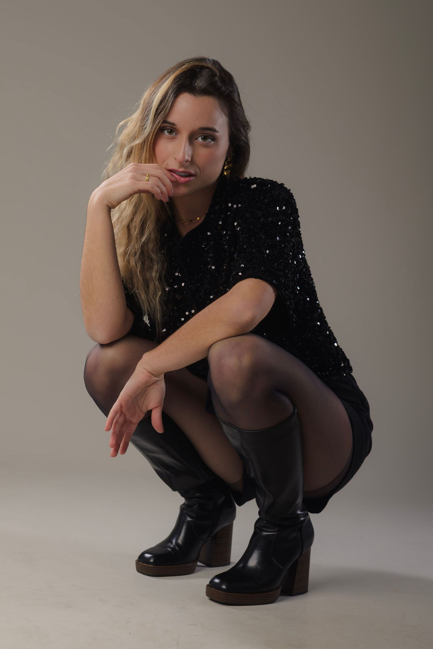 shooting photo studio sur fond blanc d'une femme accroupie habillée en noir