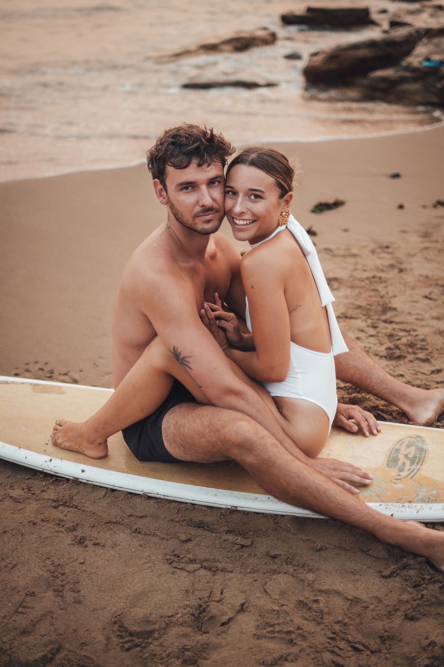shooting photo d'un couple dans l'eau en couché de soleil orange à la plage