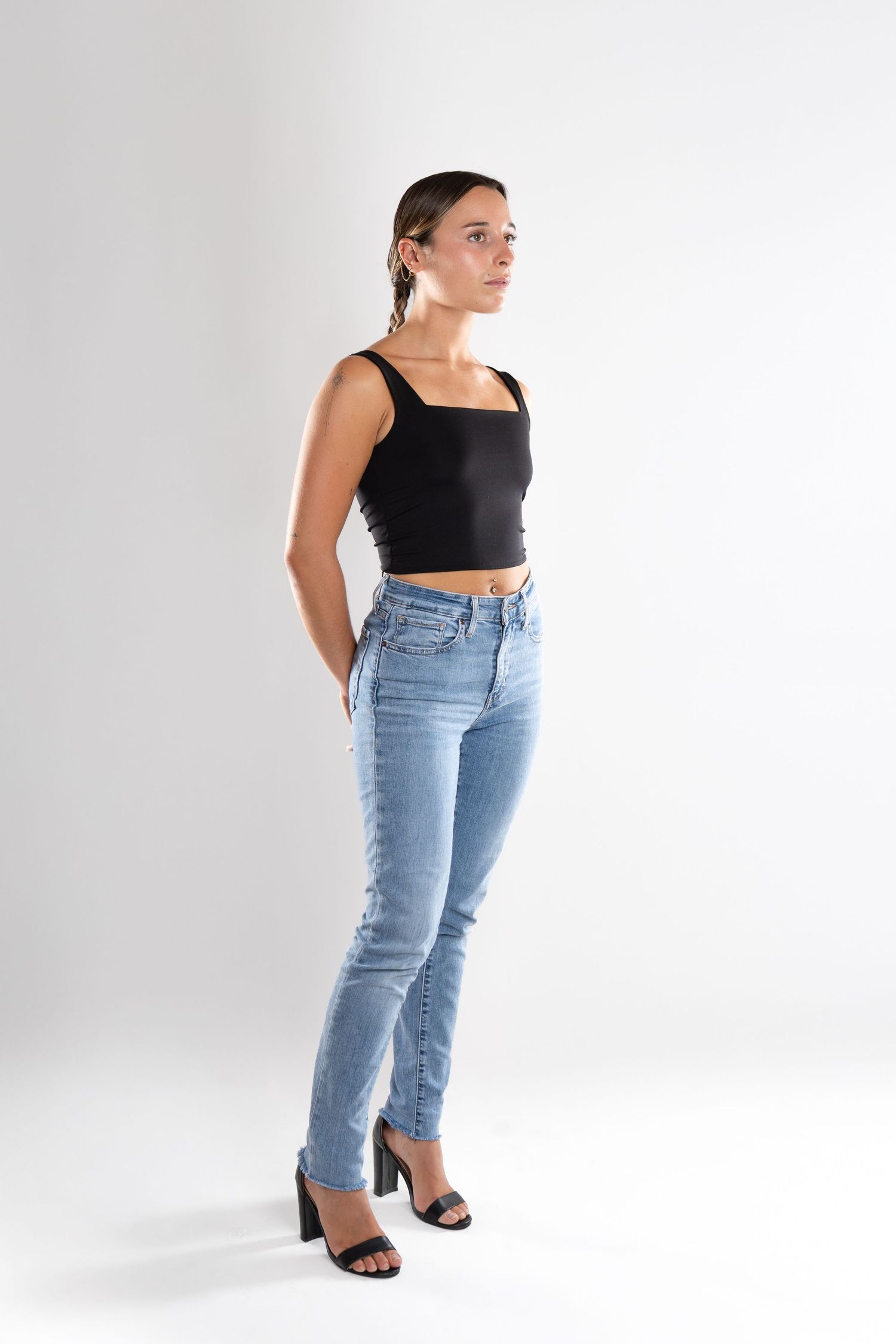 shooting photo studio en fond blanc avec une femme au centre portant un jean bleu et un top noir