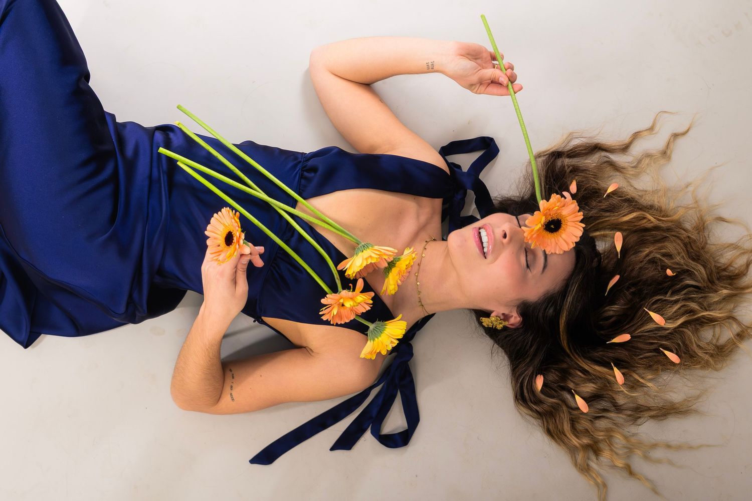 shooting photo studio sur fond blanc d'une femme habillée en bleu avec des fleurs jaunes et oranges