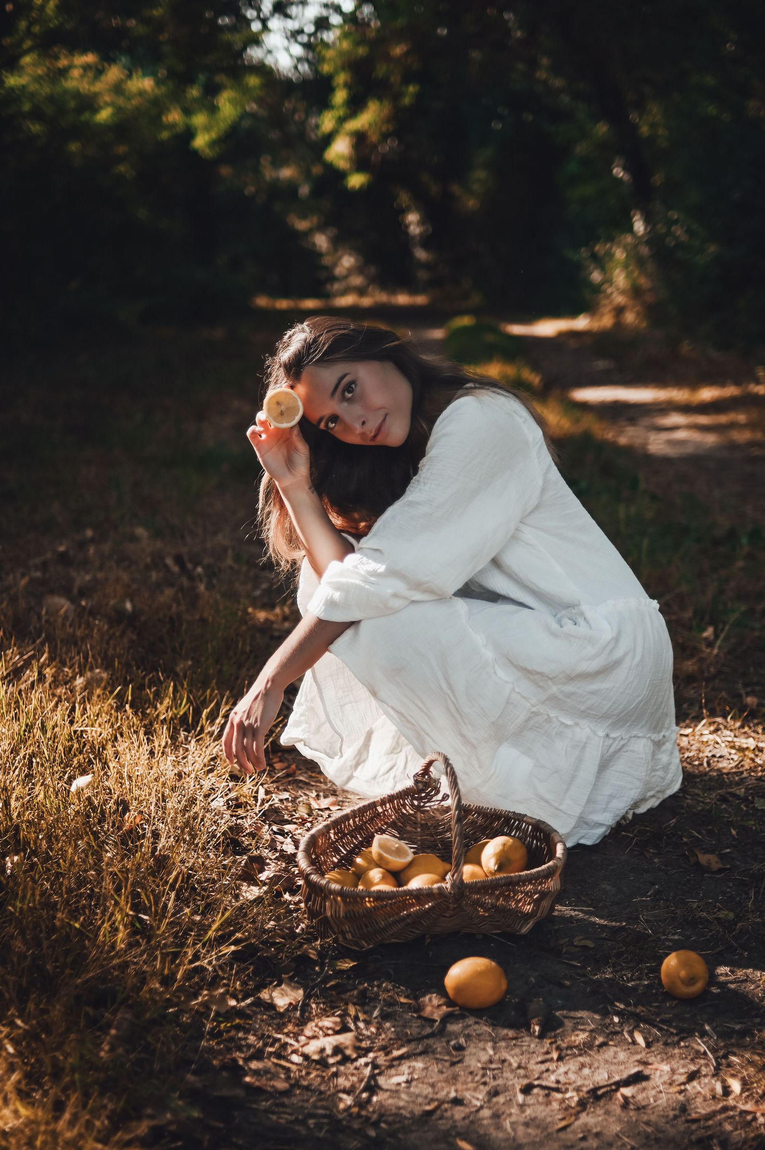 shooting photo d'une femme en robe blanche avec un panier de citron dans la foret