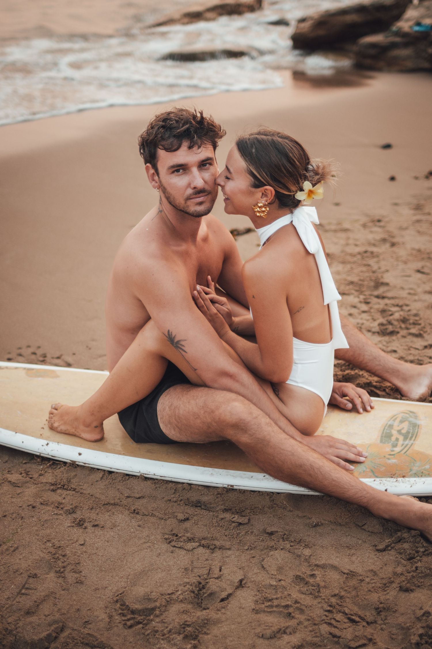 shooting photo d'un couple dans l'eau en couché de soleil orange à la plage