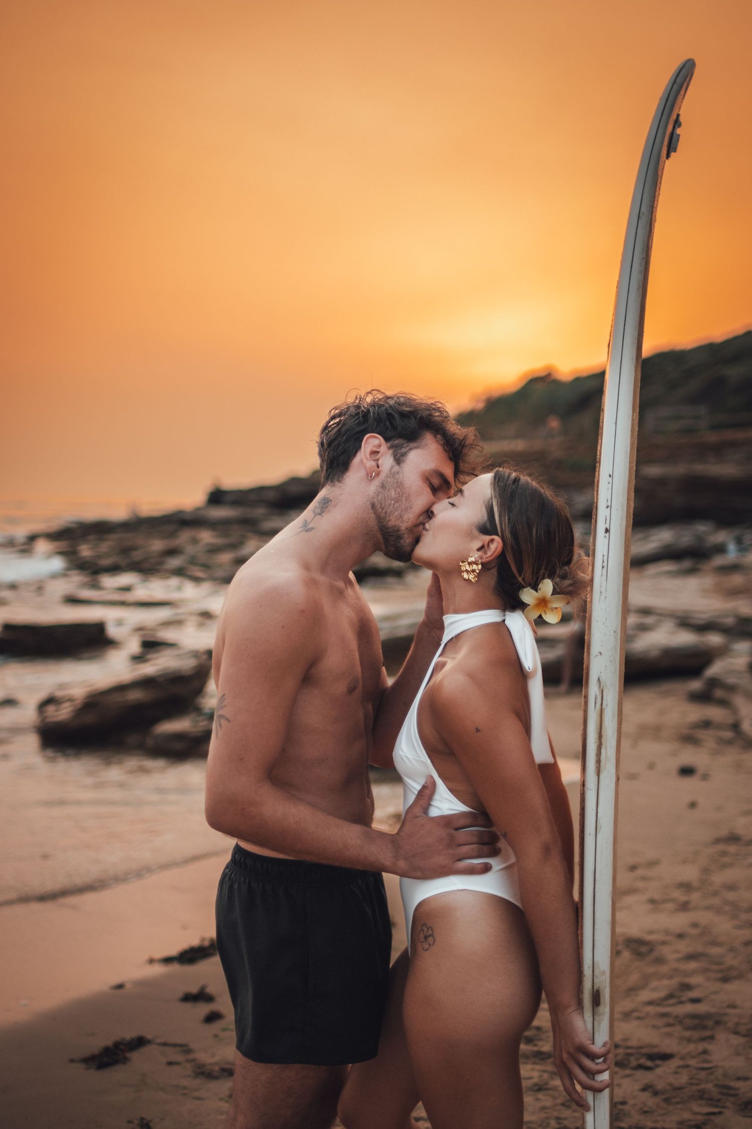 shooting photo d'un couple dans l'eau en couché de soleil orange à la plage