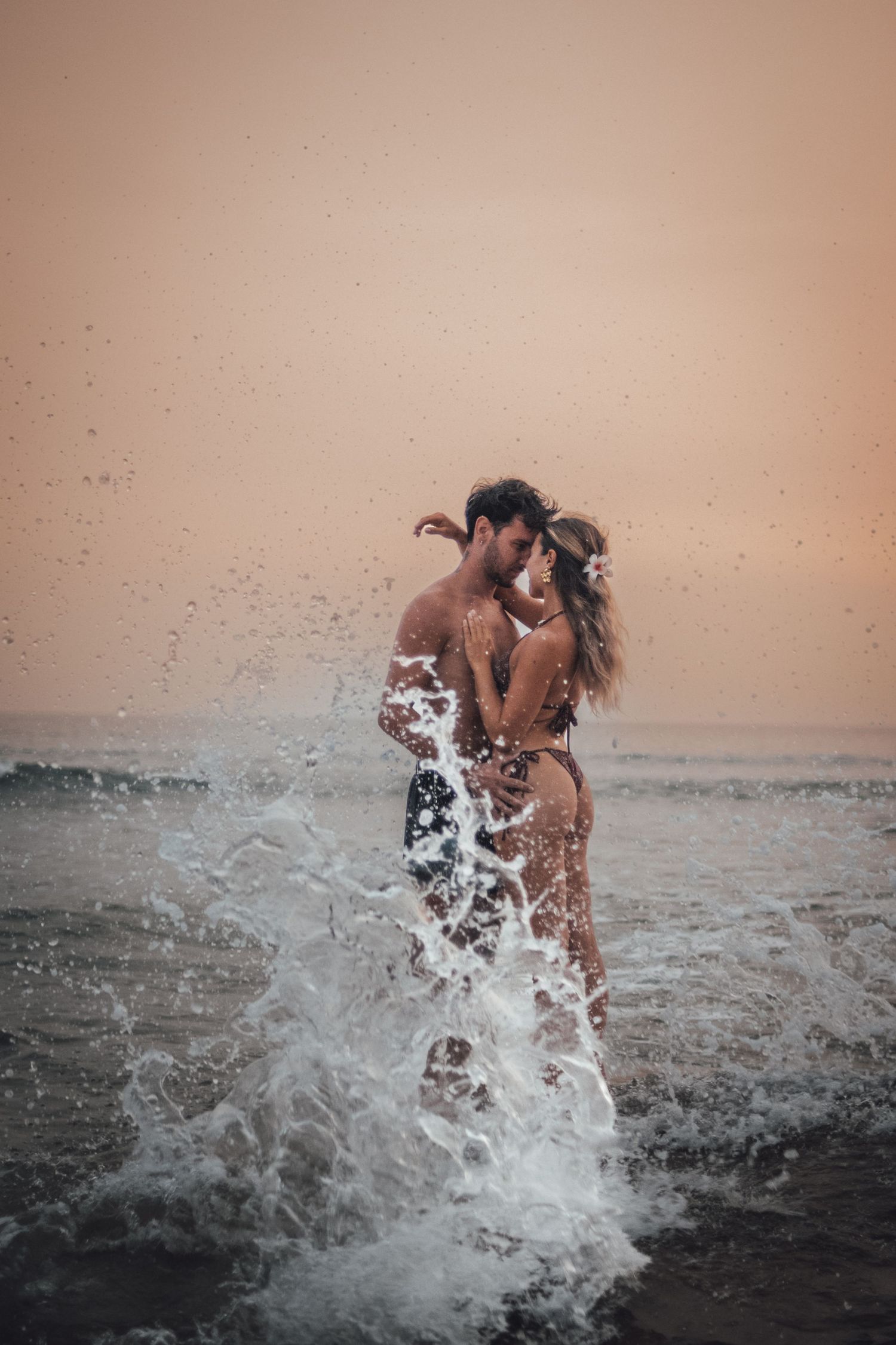 shooting photo d'un couple dans l'eau en couché de soleil orange à la plage