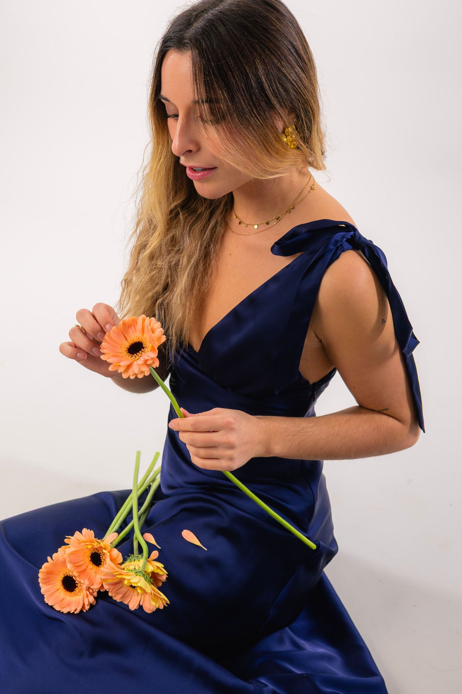 shooting photo studio sur fond blanc d'une femme habillée en bleu avec des fleurs jaunes et oranges