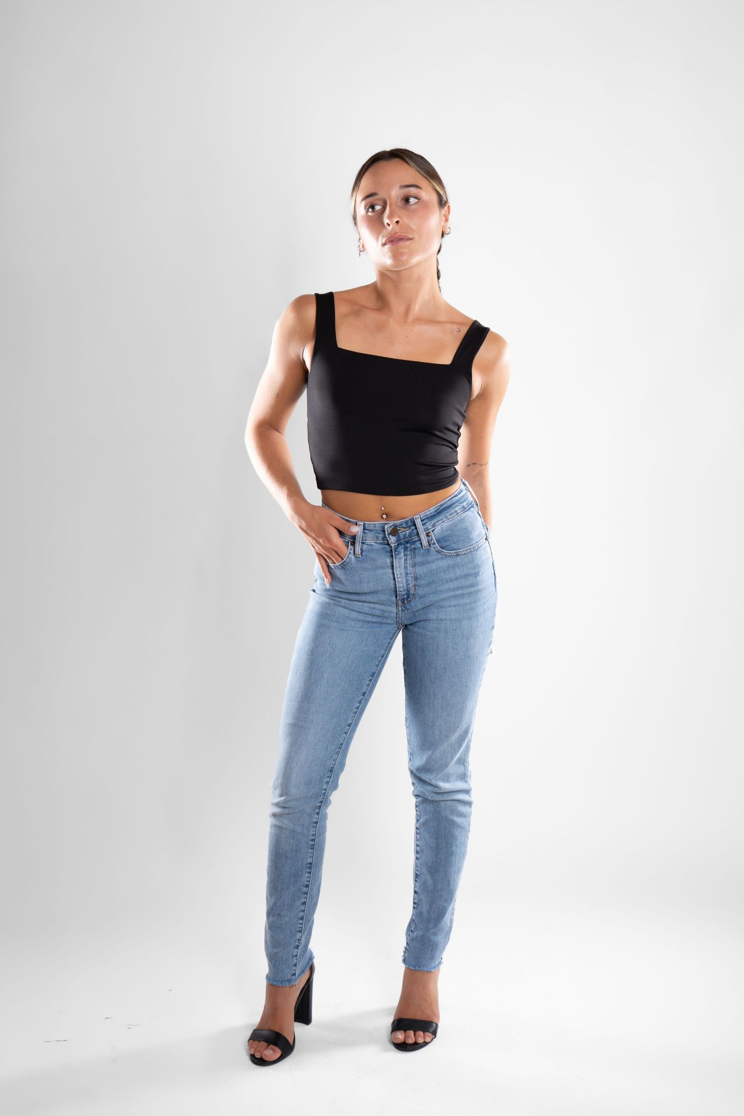 shooting photo studio en fond blanc avec une femme au centre portant un jean bleu et un top noir