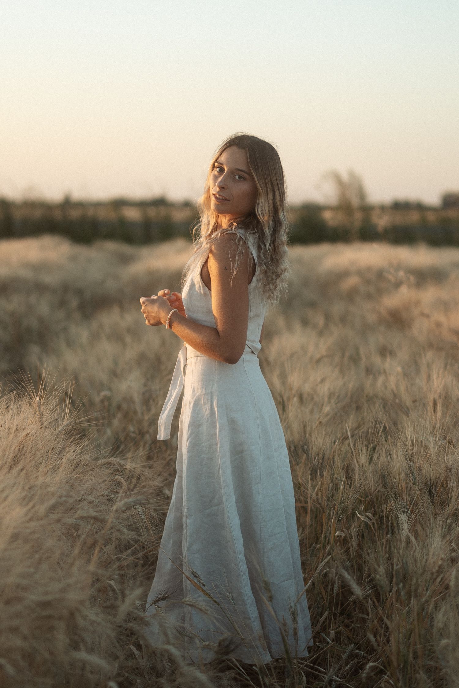 modele photo blonde dans un champ de blé avec une robe beige