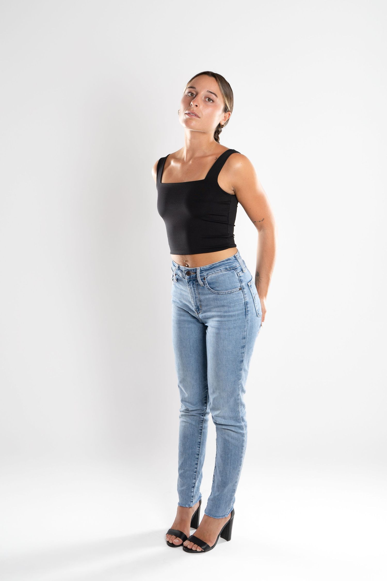shooting photo studio en fond blanc avec une femme au centre portant un jean bleu et un top noir