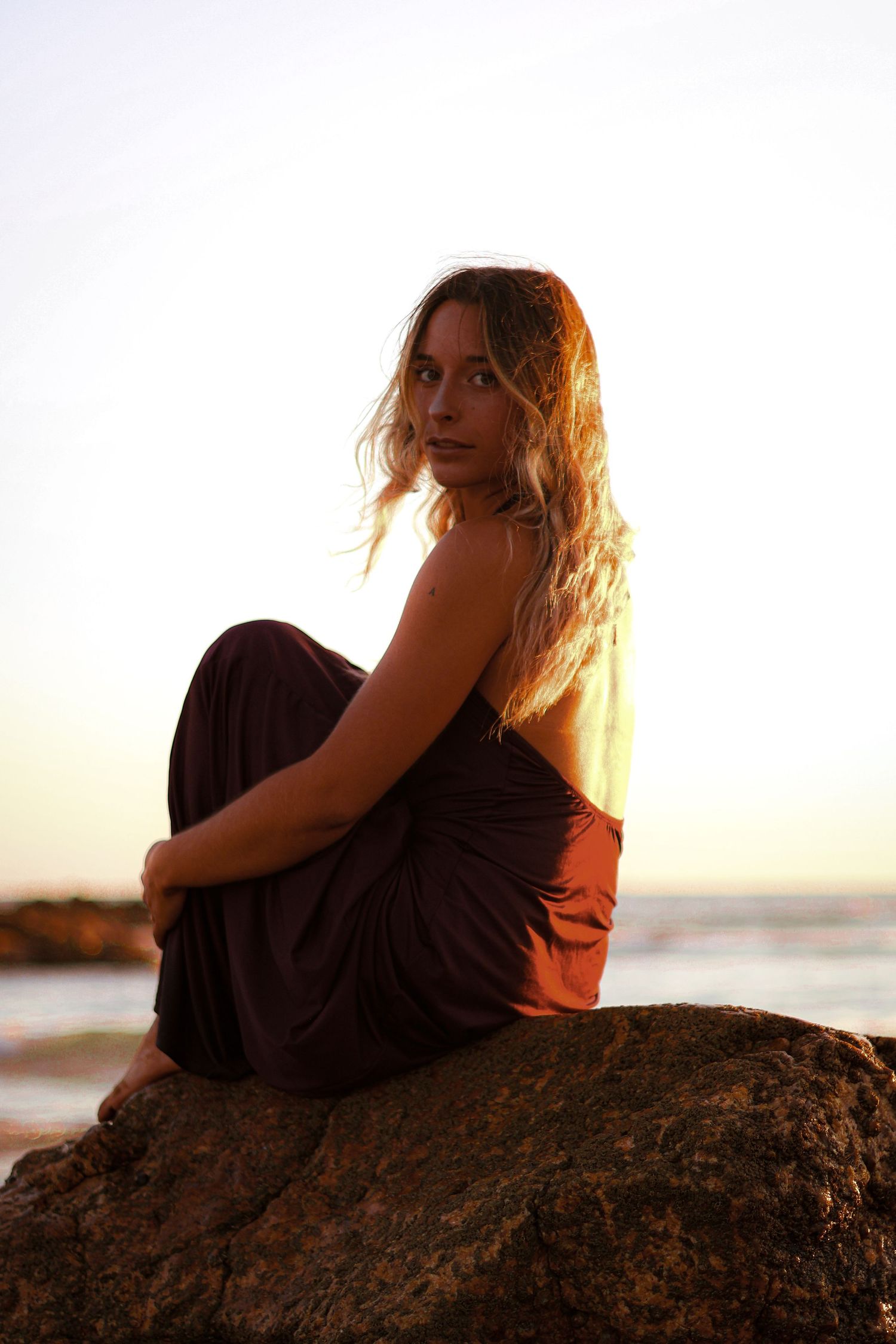 shooting photo d'une femme assise sur un roche en bord de mer