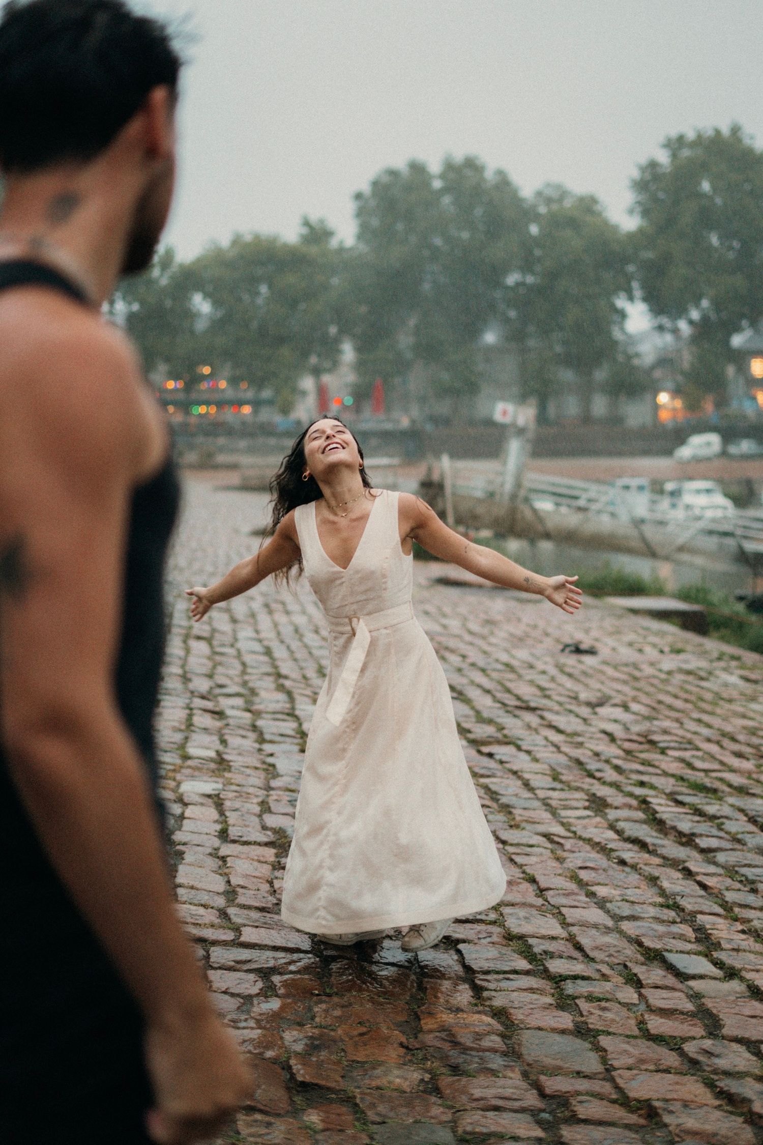 couple  sur le port d'Agers lors d'un shooting photo, on peut apercevoir un homme en vêtements noir et d'une femme en robe beige