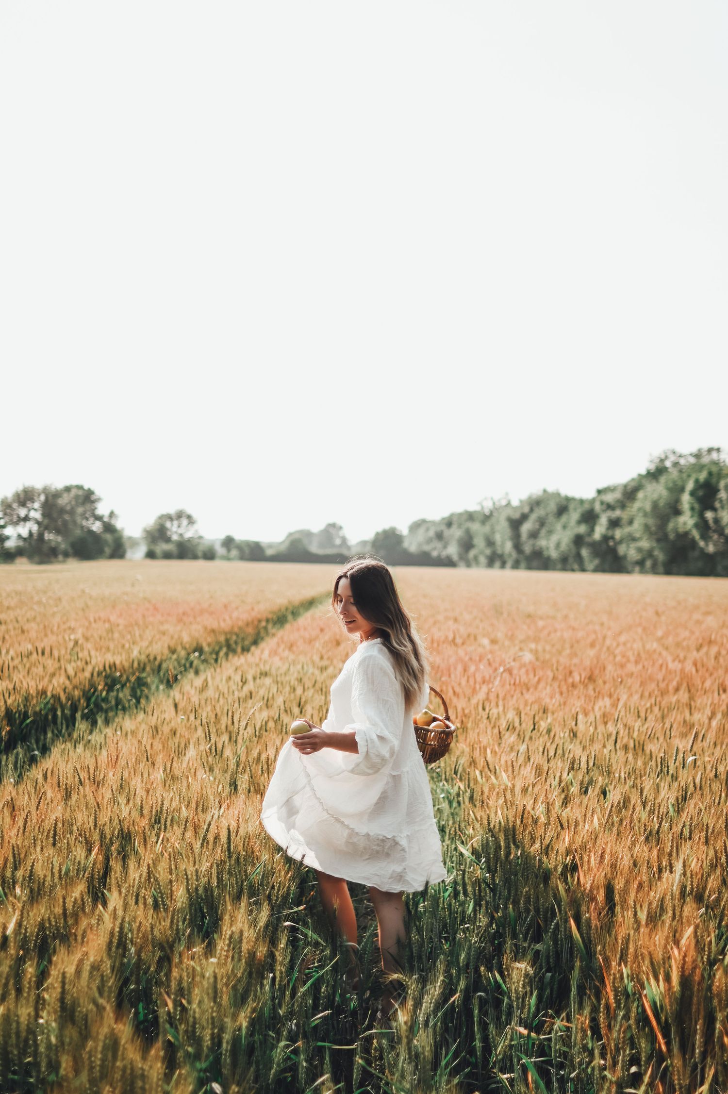 shooting photo d'une femme en robe blanche avec un panier de citron dans un champ de blé