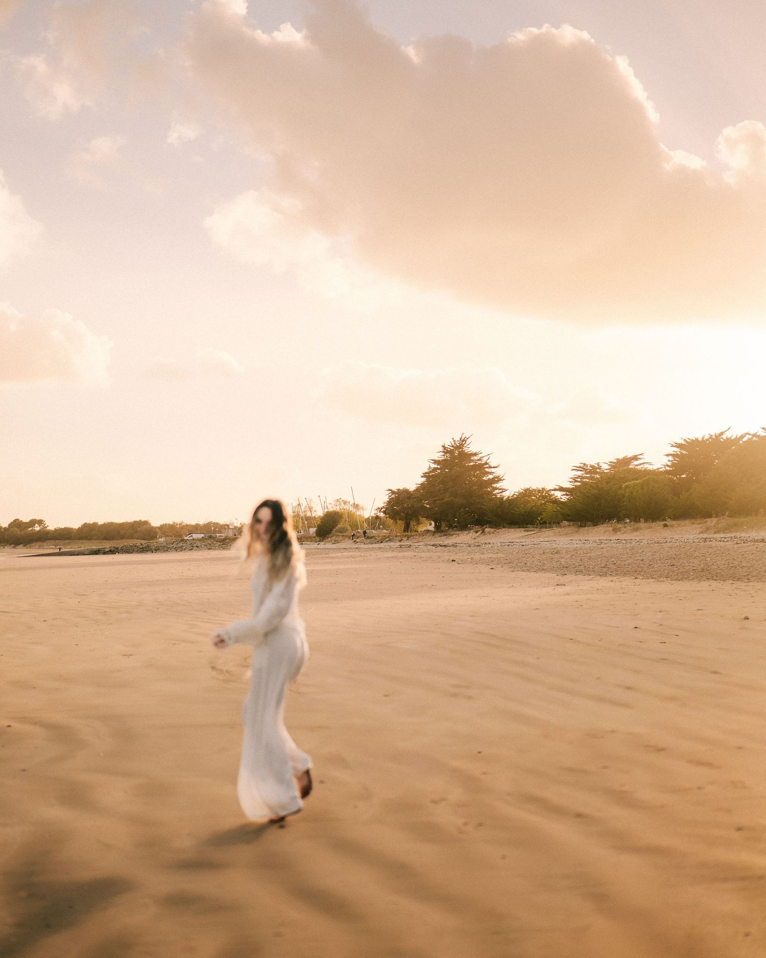 couché de soleil sur la plage avec une femme habillée en blanc