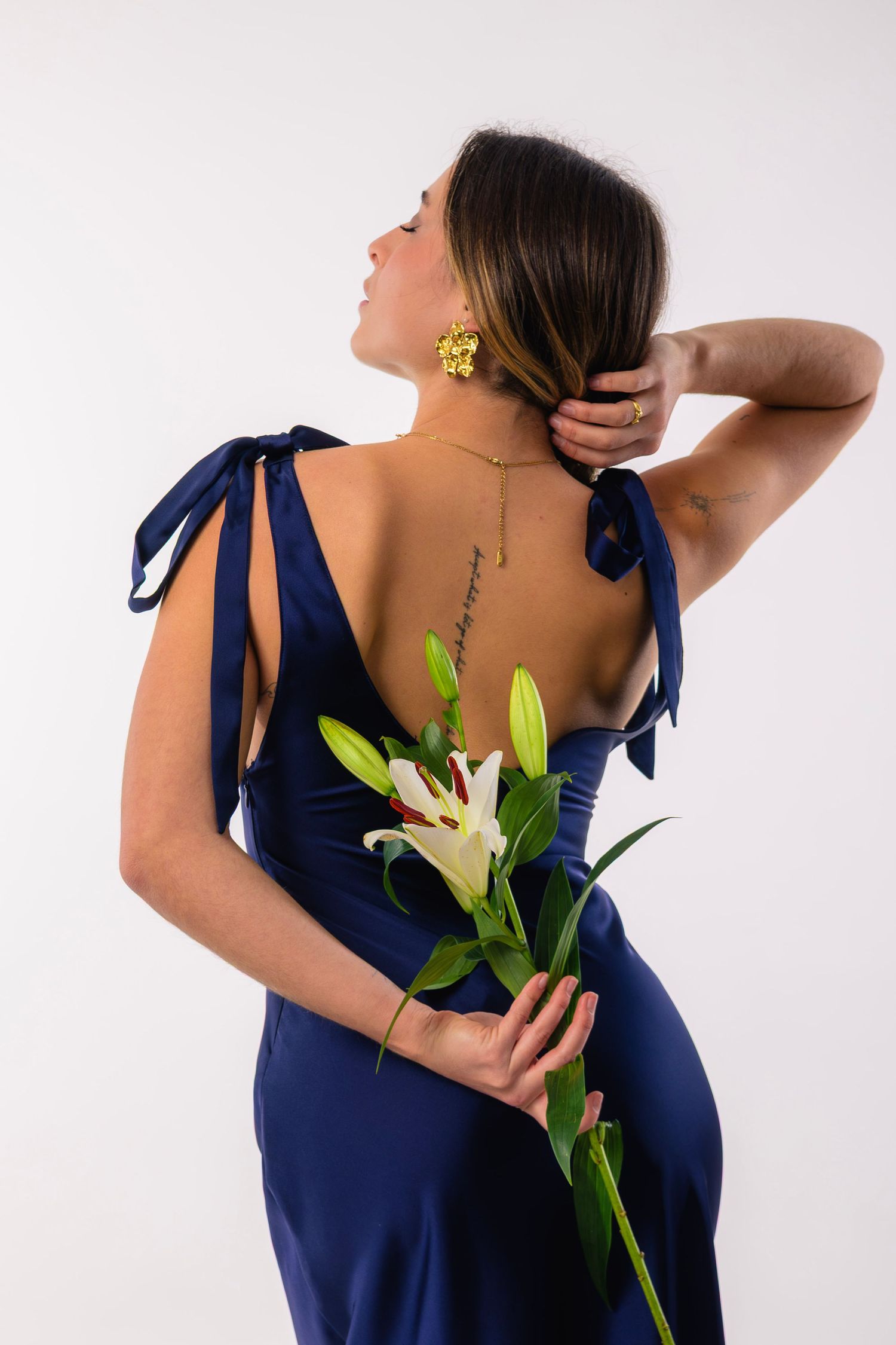 shooting photo studio sur fond blanc d'une femme habillée en bleu avec un bouquet de fleurs dans le dos