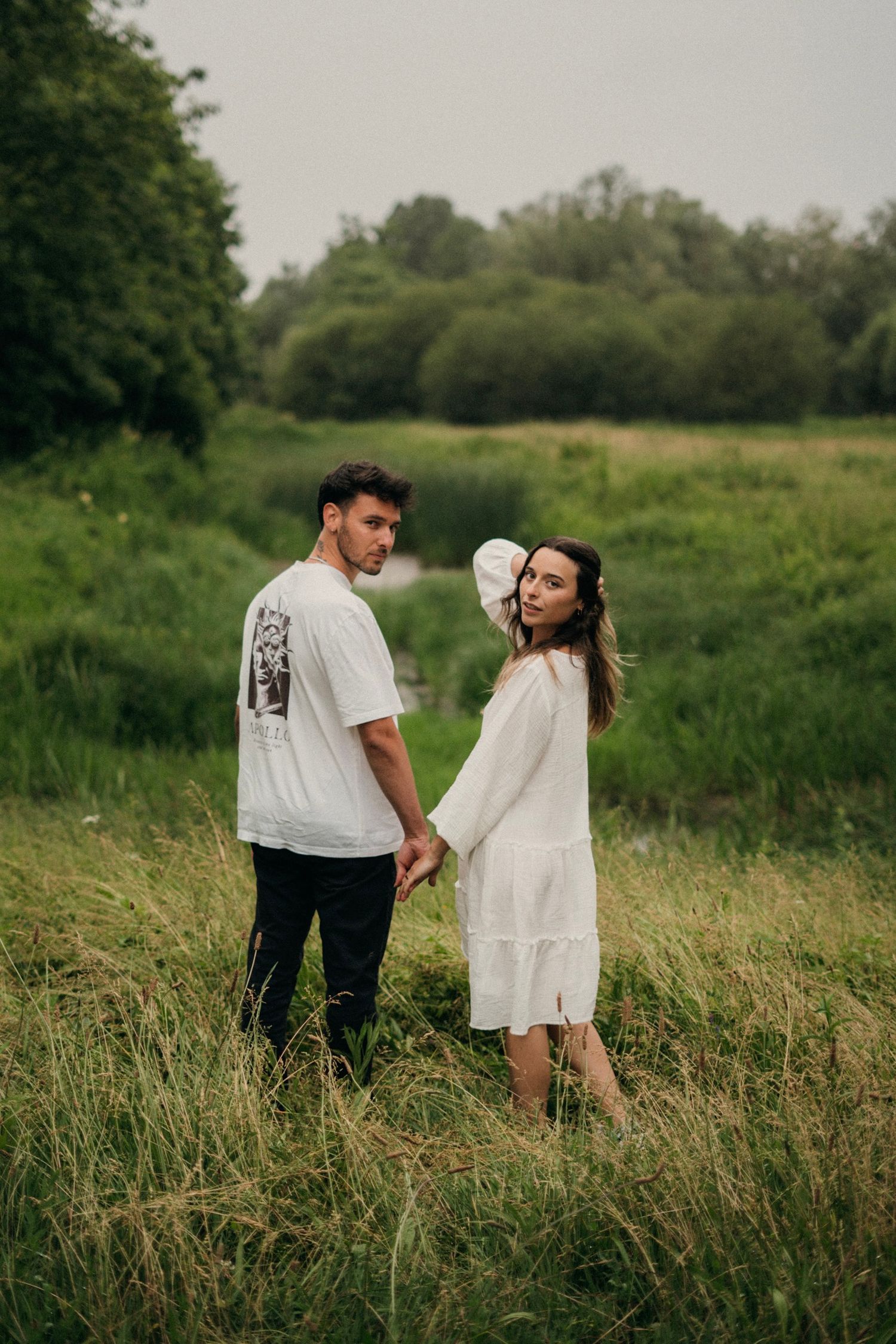 shooting photo d'un couple se tenant la main dans un champ