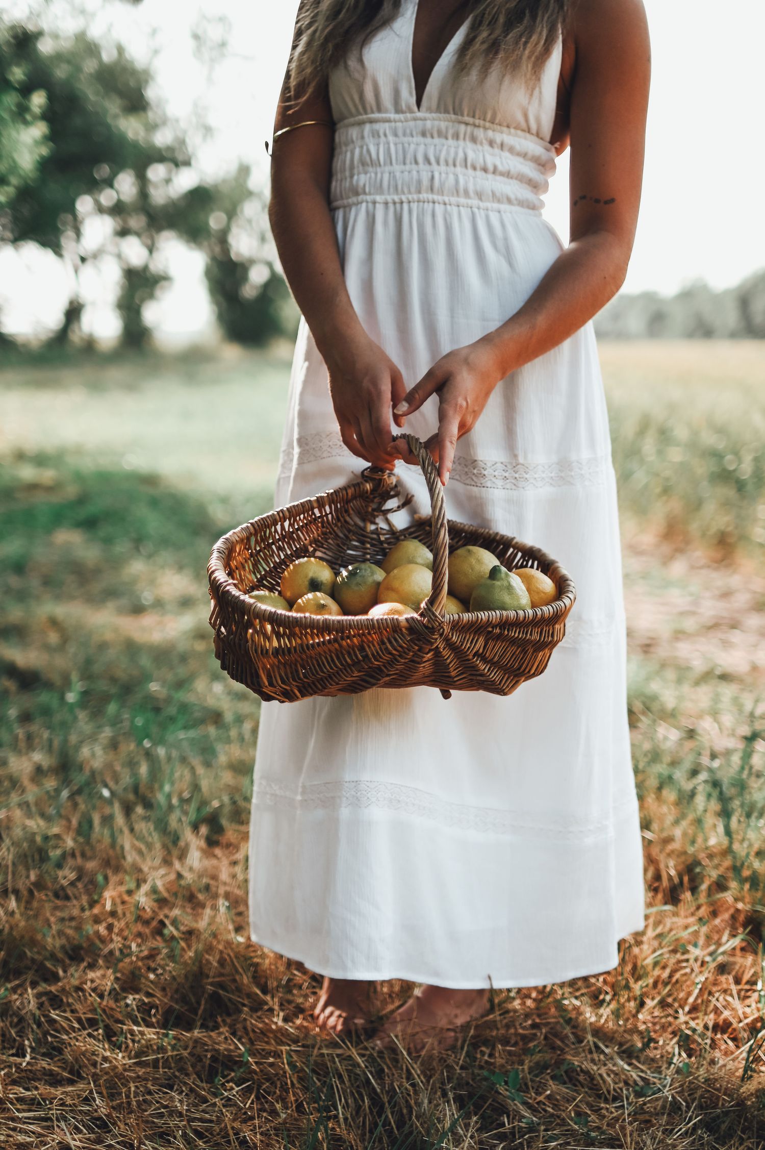 shooting photo d'une femme en robe blanche avec un panier de citron dans la foret