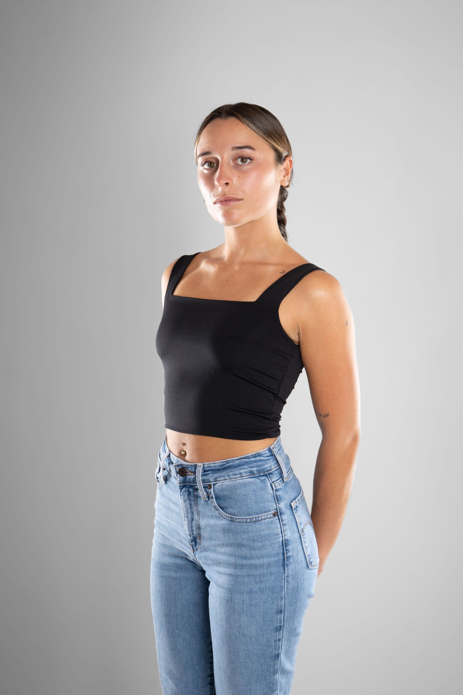 shooting photo studio en fond blanc avec une femme de profil portant un jean bleu et un top noir