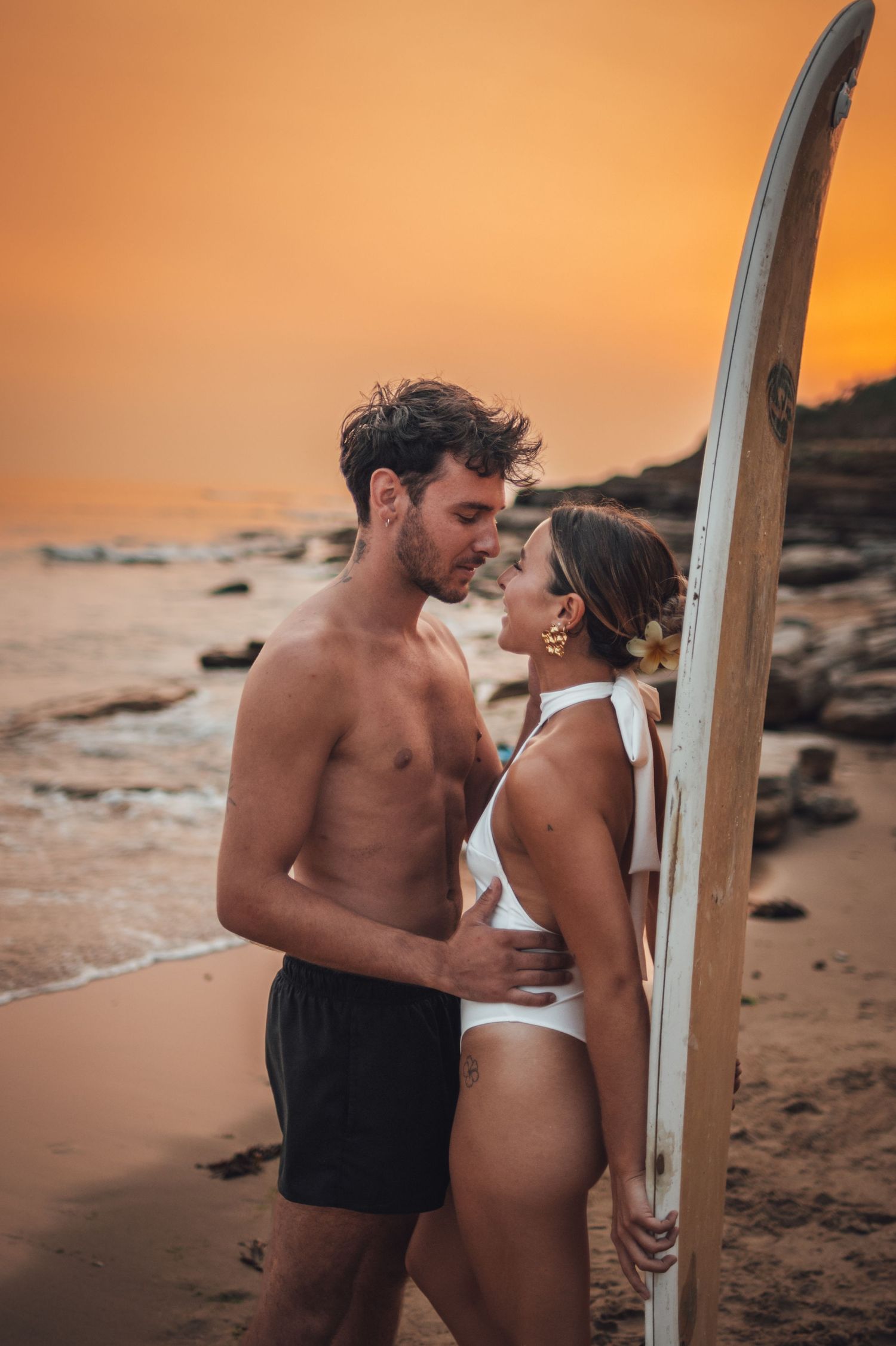 shooting photo d'un couple dans l'eau en couché de soleil orange à la plage