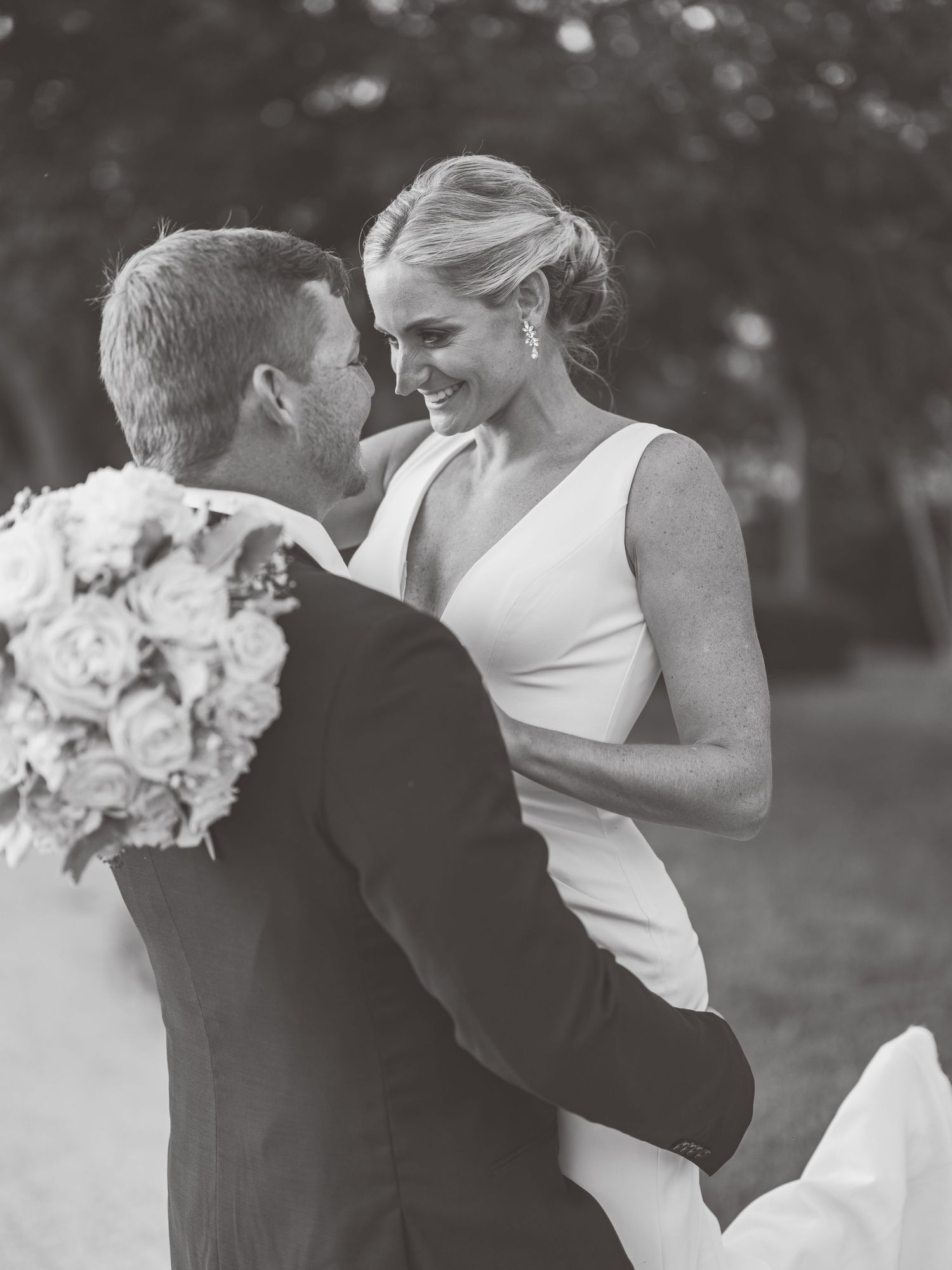 A romantic black and white wedding photo series showing a couple embracing and sharing tender moments outdoors.