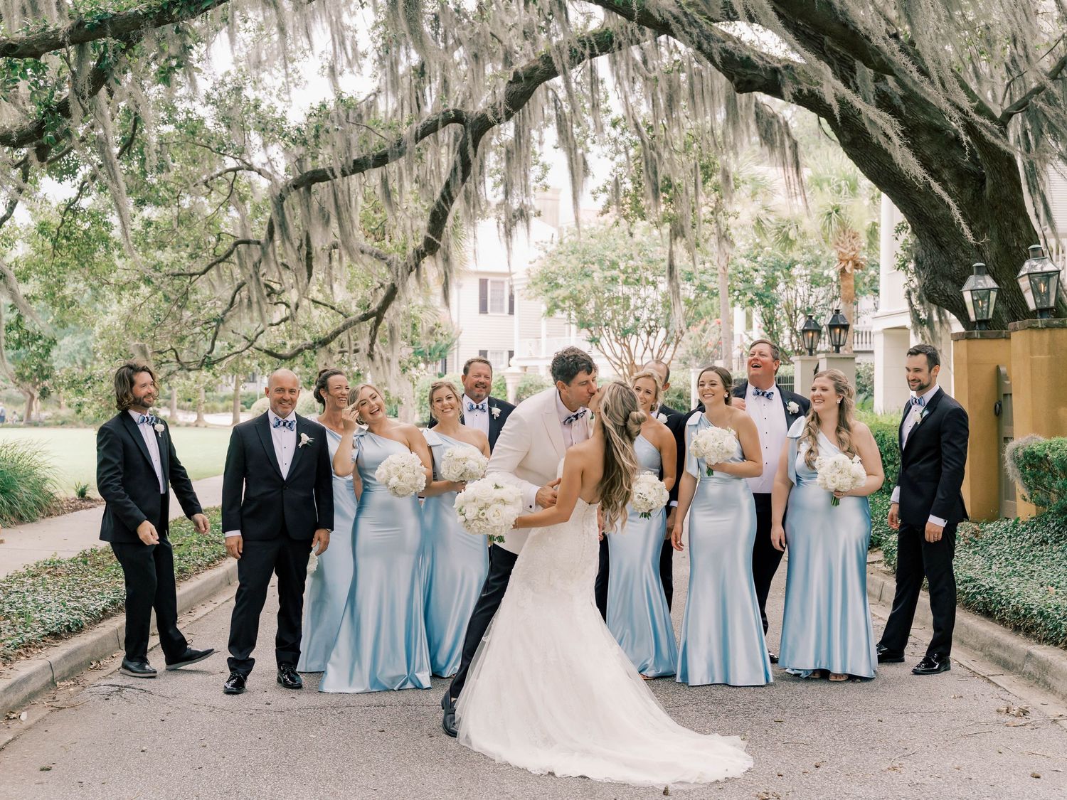 Wedding party in light blue dresses posed under Spanish moss draped trees.