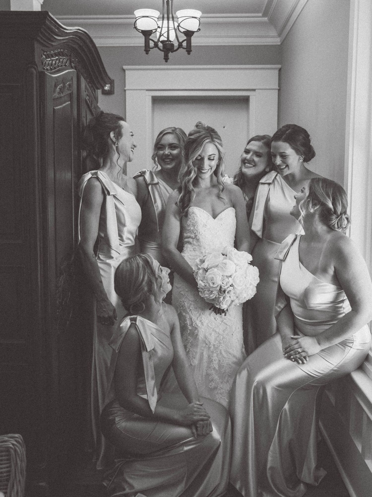 Black and white candid photo of wedding party preparations indoors.