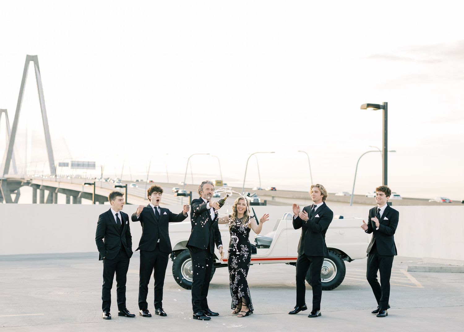 Wedding party jumps in unison on a beach during sunset creating a fun silhouette photo.