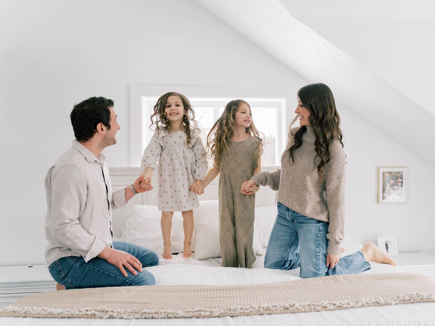 Three people sit together on a light carpet in a bright white room with minimalist decor.