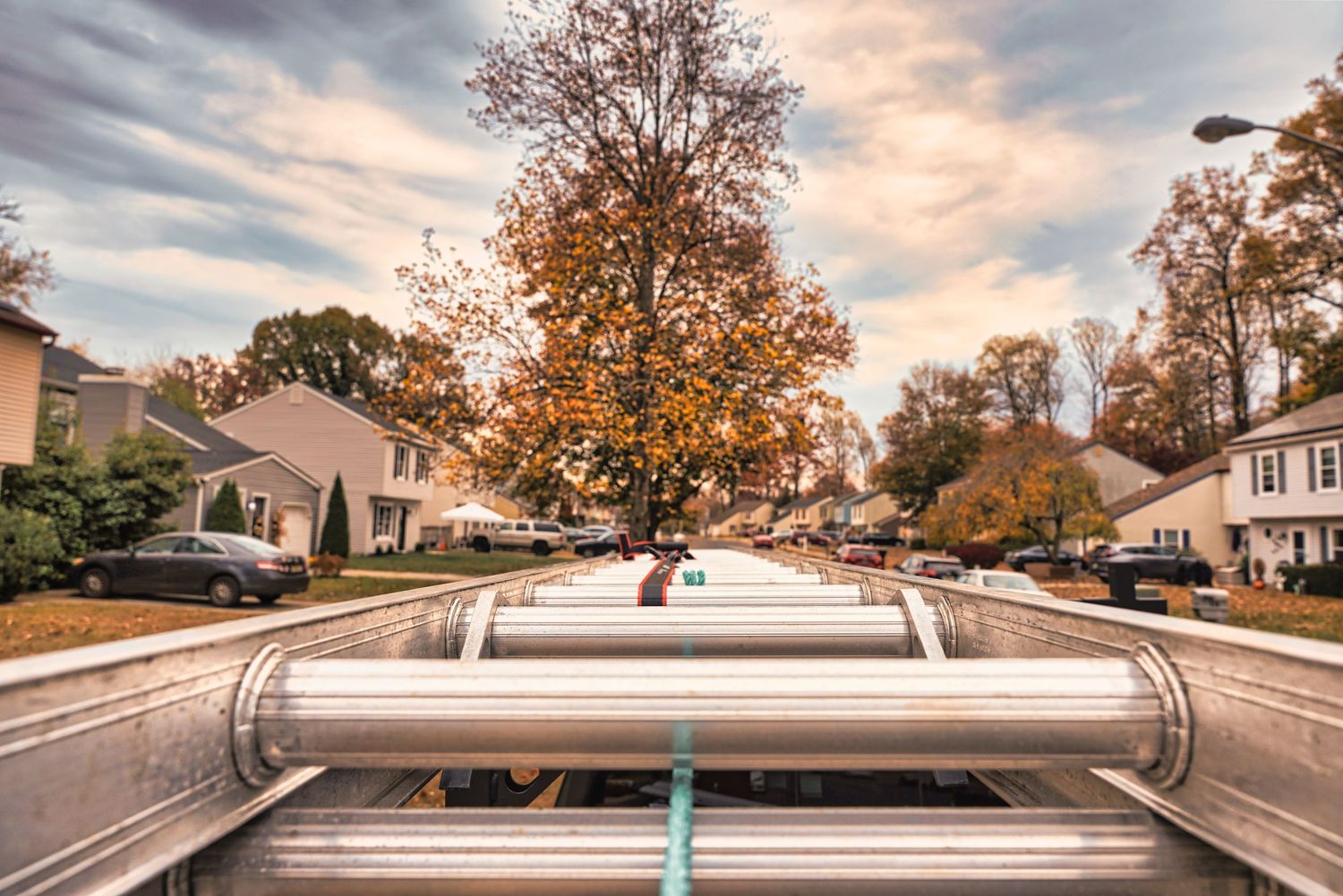 A roof rack mounted on a car viewed from above with autumn trees and suburban houses in the background at sunset.