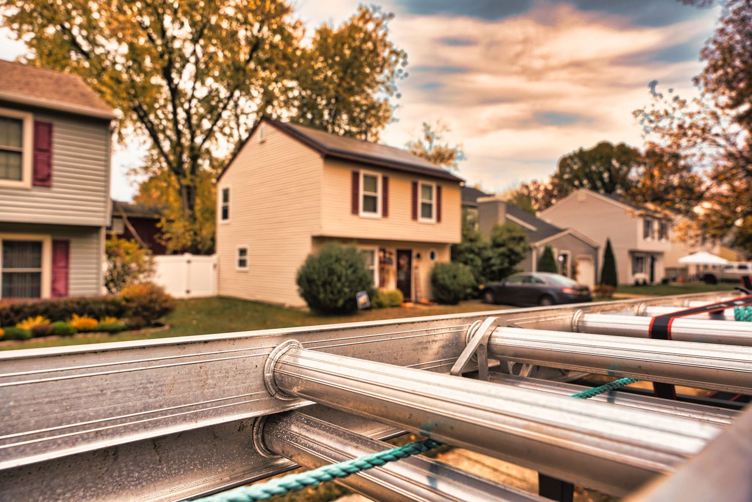 A series of solar panel installations on residential rooftops during sunset with orange-tinted clouds in the sky.