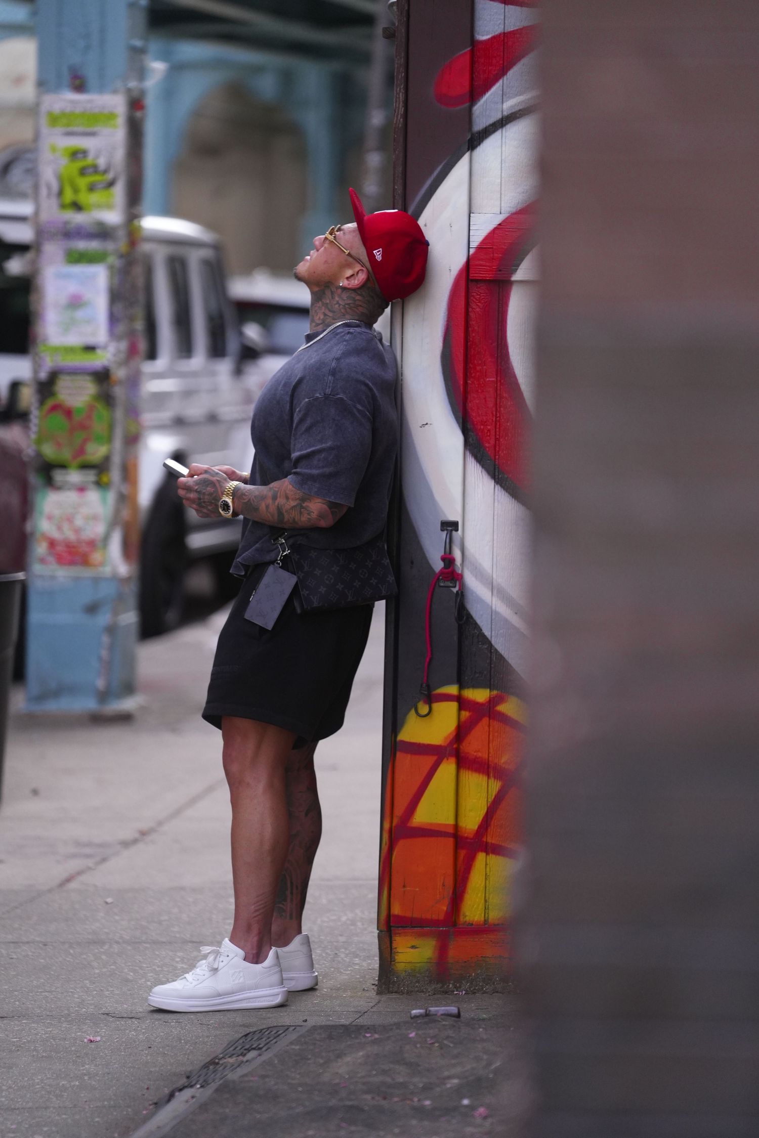 A series of four photos showing someone leaning against a colorfully painted wall on a city street.