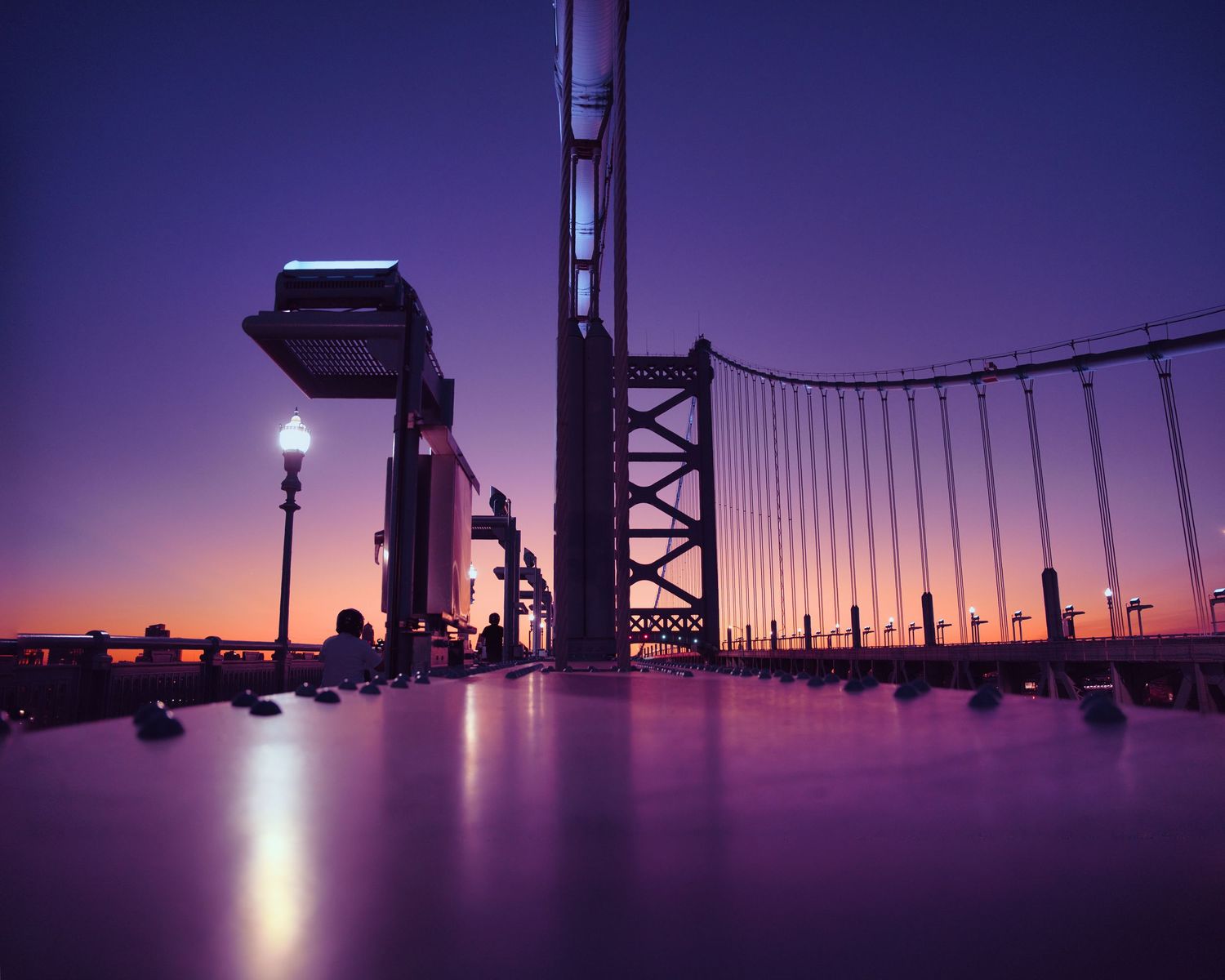 Silhouette of the Benjamin Franklin Bridge over Delaware River at dusk with purple sky in Philadelphia.