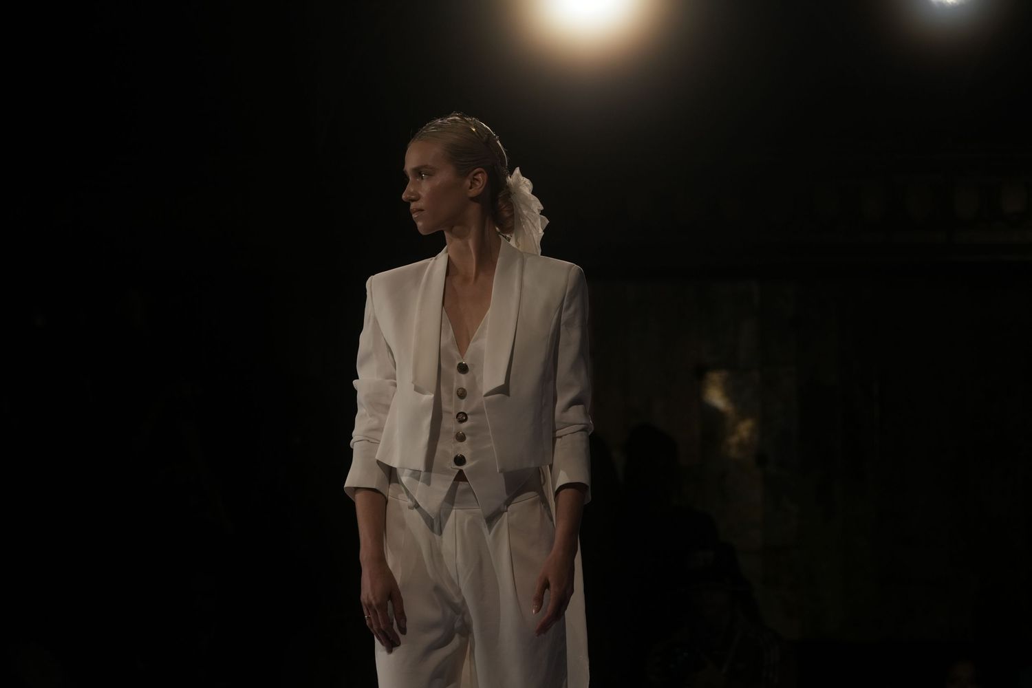 A series of fashion photographs showing a model in white outfits against a dark background.