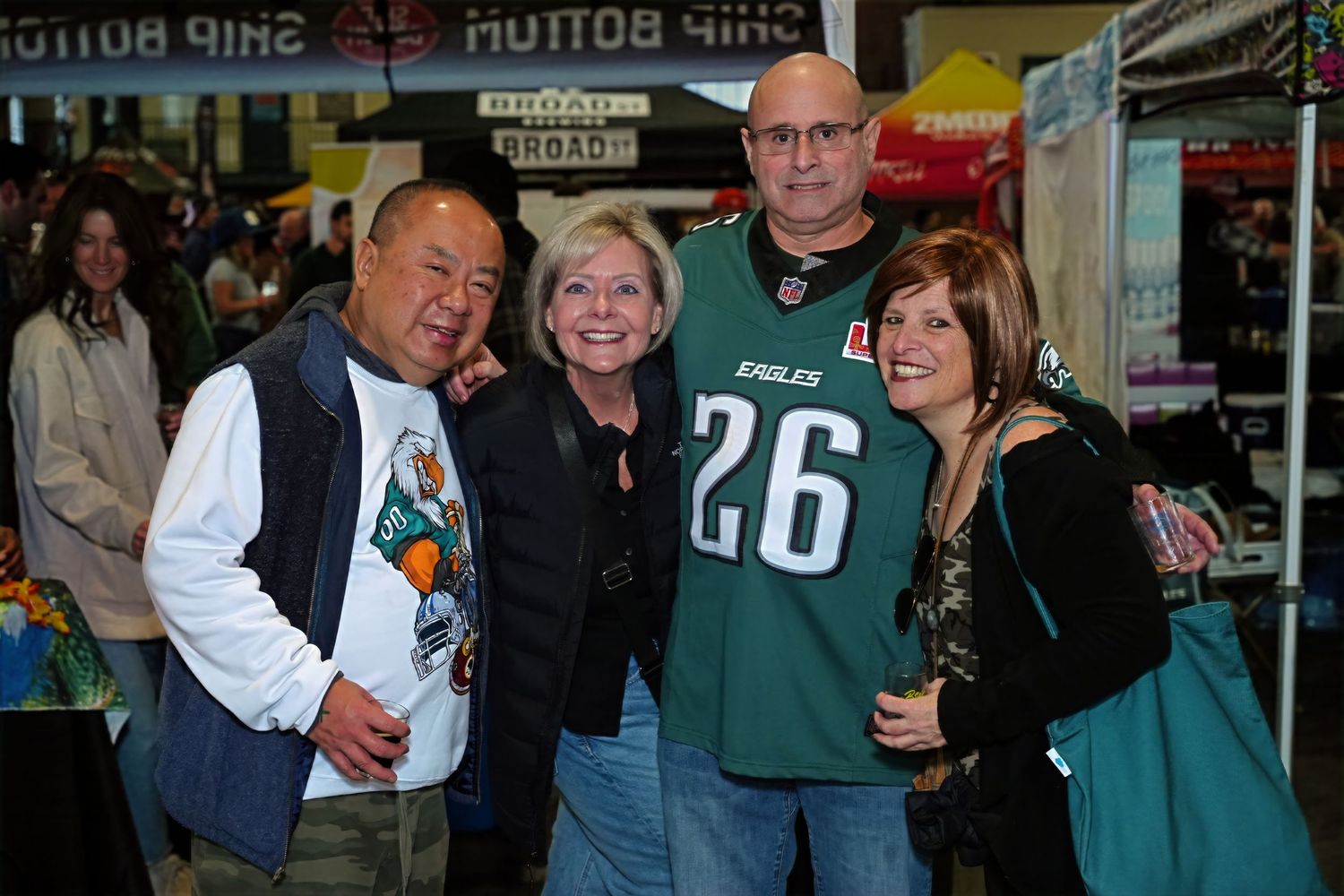 Group of sports fans pose together at a retail location wearing Eagles merchandise and casual attire.