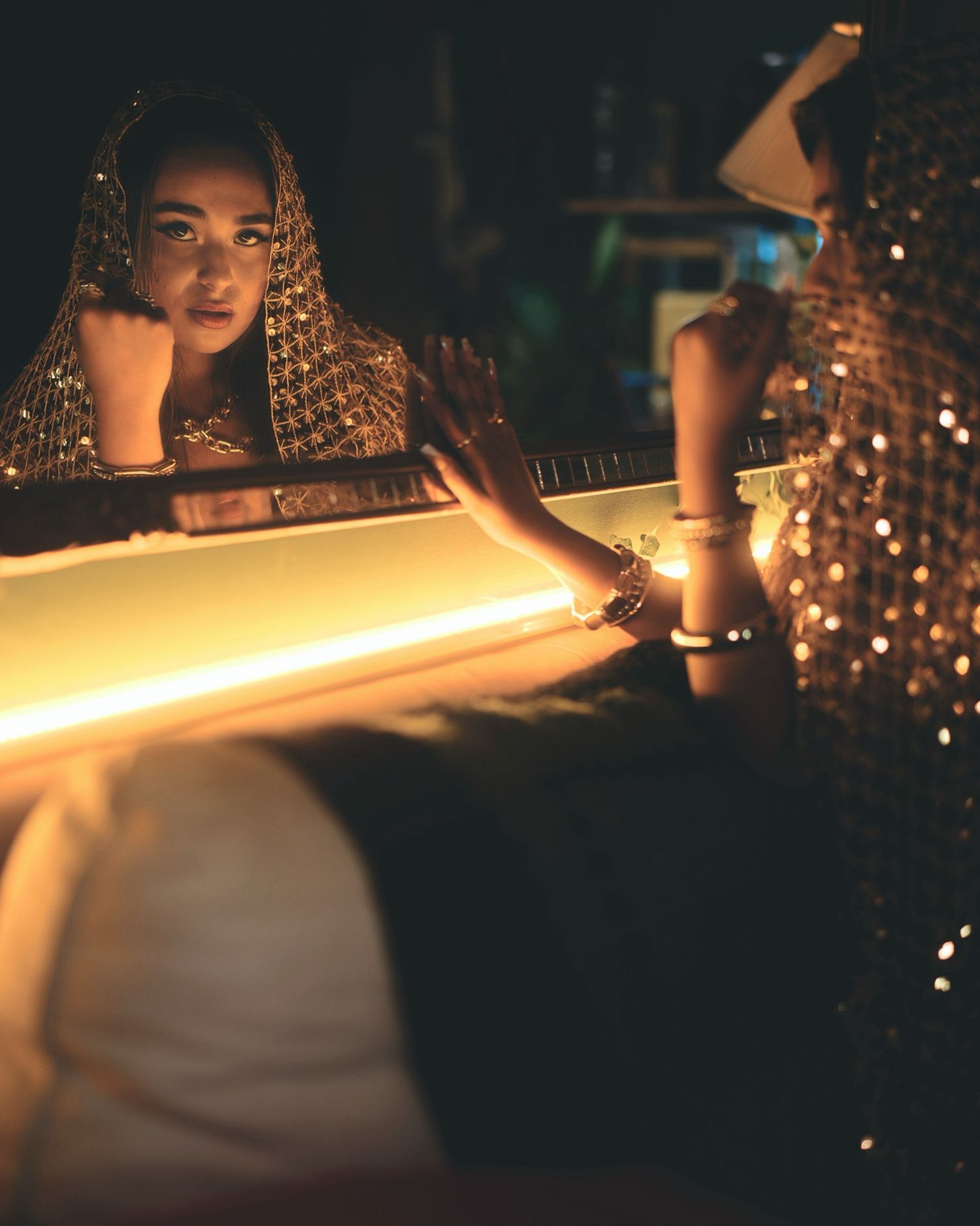 Person strikes a match in dark room creating warm glow and reflective sparkles on decorative elements.