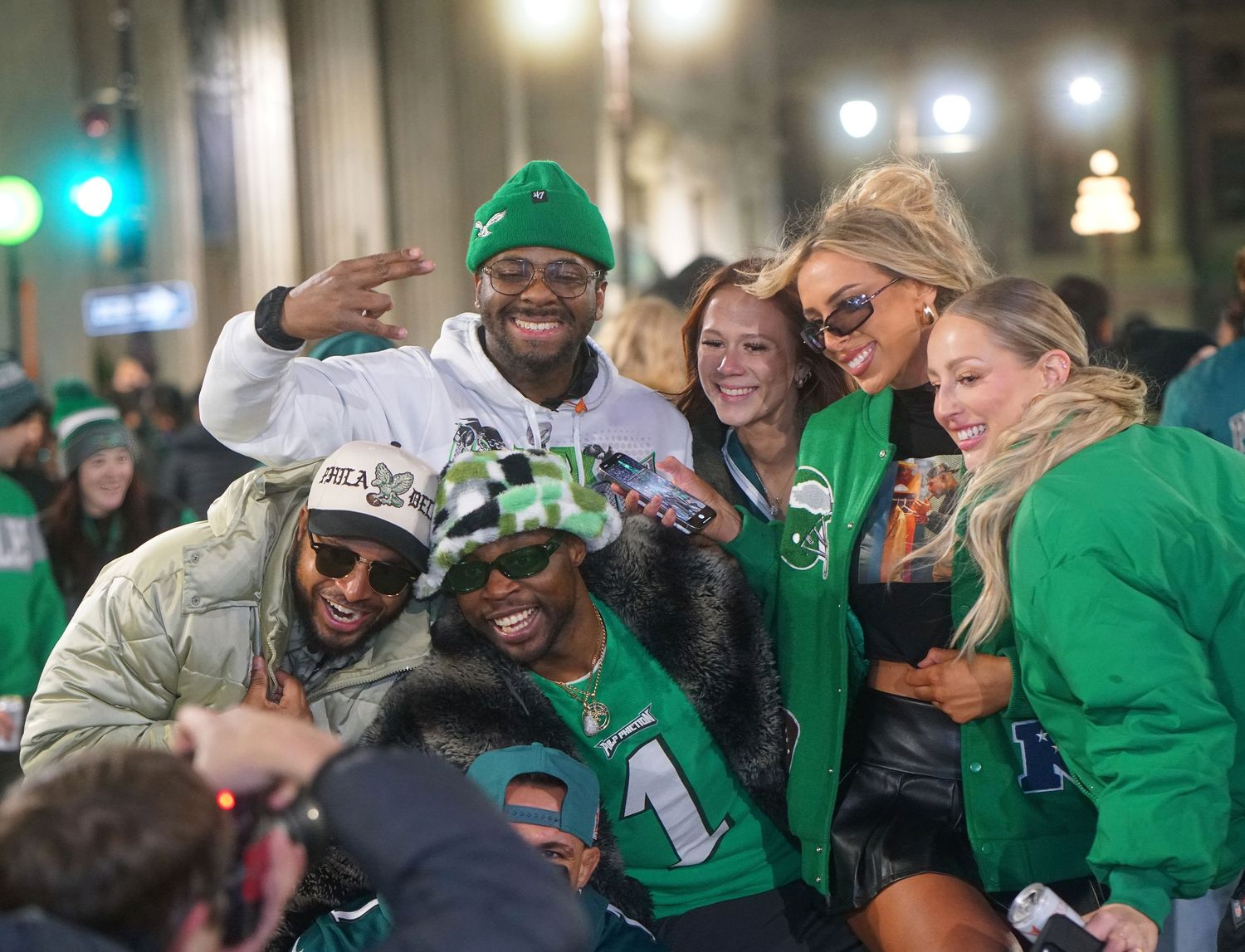 A cheerful group of people wearing green celebrating together during a festive nighttime street celebration.