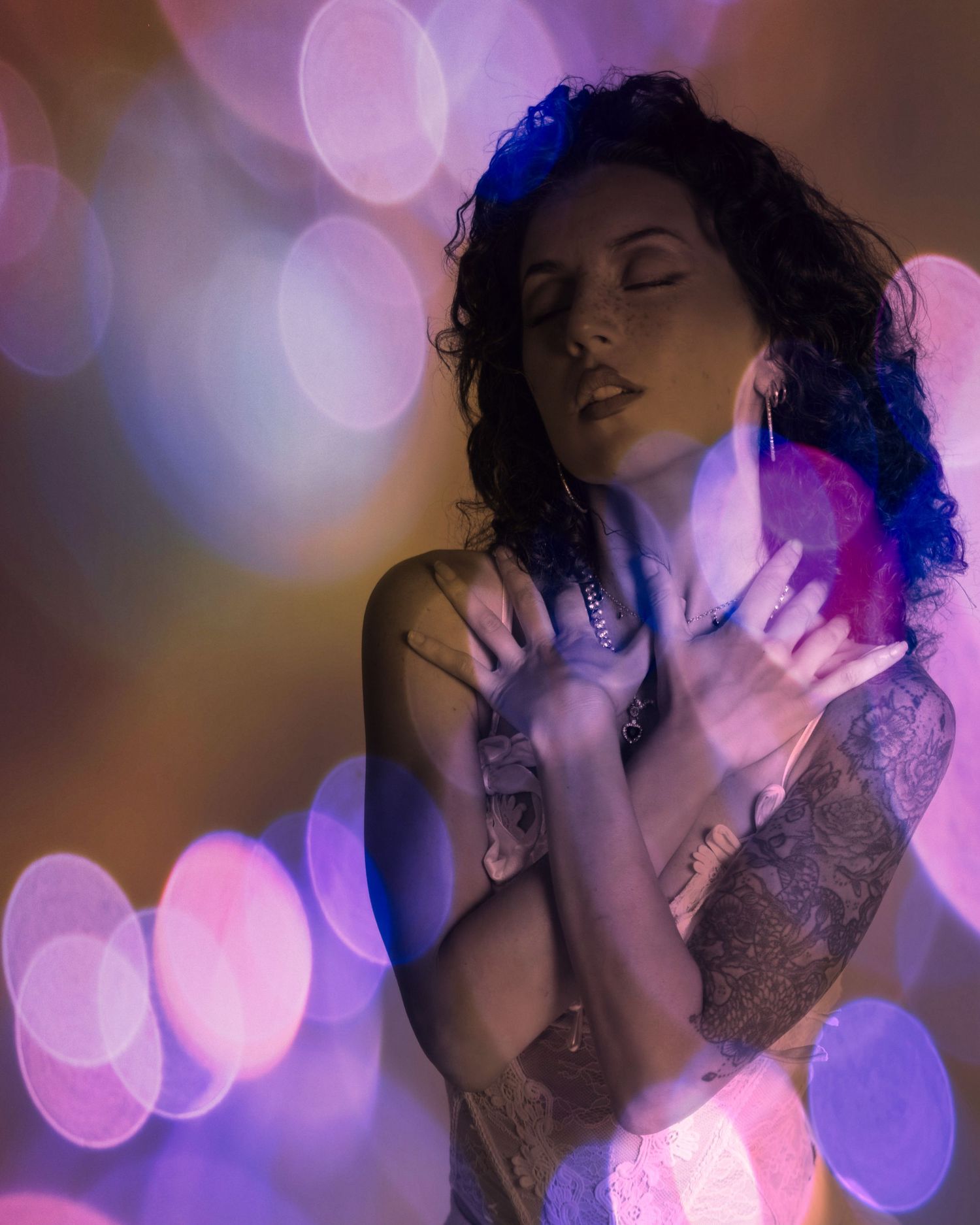 Artistic portrait against purple bokeh lights showing expressive movement and emotion in soft lighting.