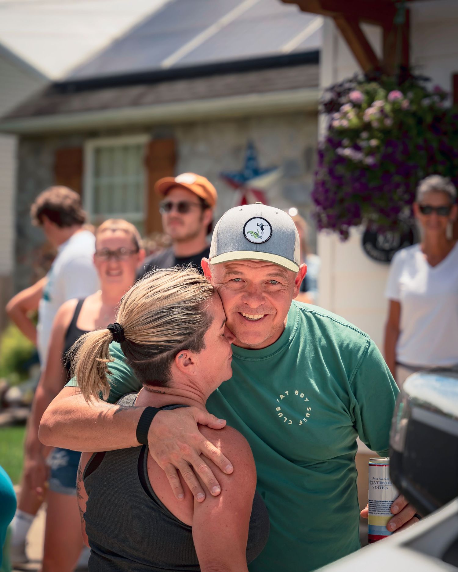 A person wearing a green shirt hugs someone while smiling outdoors at what appears to be a sporting event.